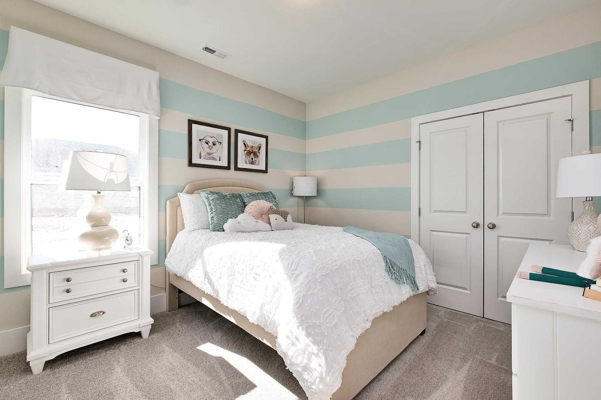 Cozy girl's bedroom at Newby Chapel in Athens Alabama with aqua striped walls, plush twin bed, and framed dog art