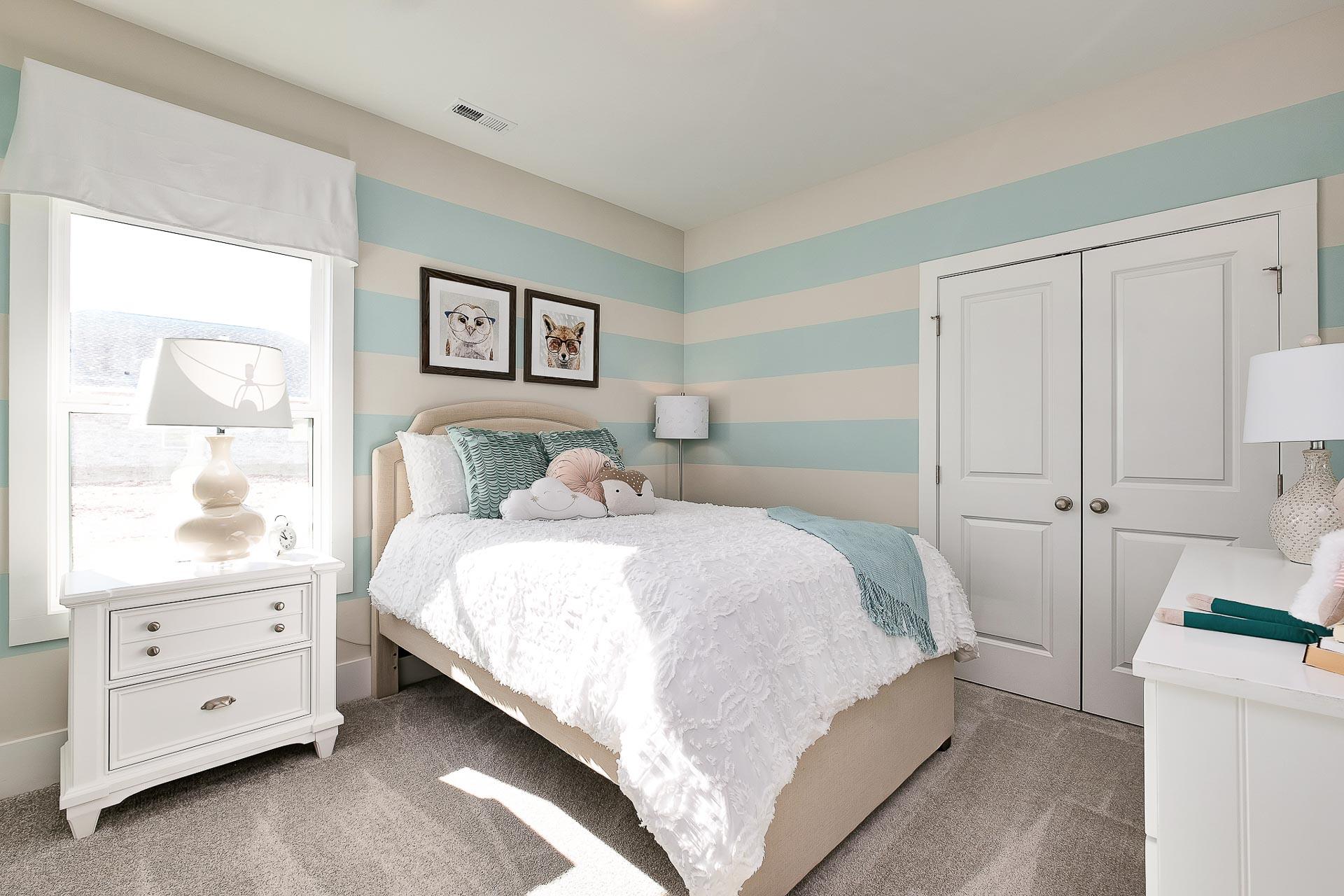 Cozy girl's bedroom at Newby Chapel in Athens Alabama with aqua striped walls, plush twin bed, and framed dog art