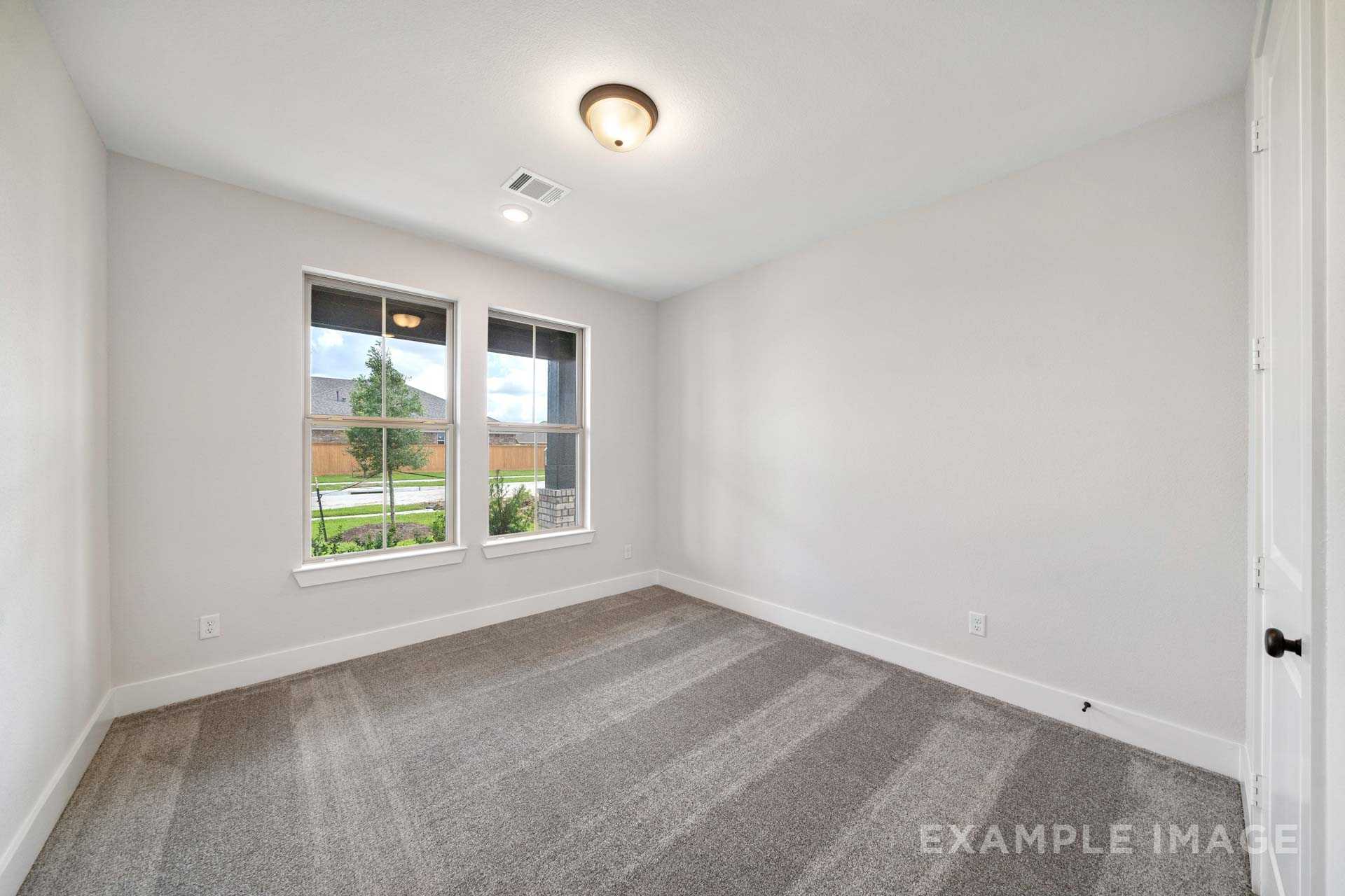 Spacious secondary bedroom in The Victoria with large windows, neutral gray walls, and carpeted floor