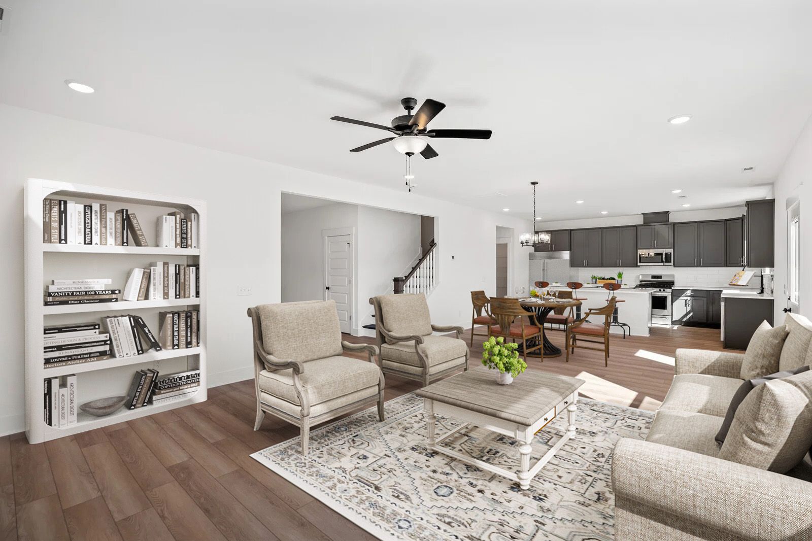 Open-concept living room in Carellton Gallatin TN home with hardwood floors, beige armchairs, white bookshelves, rug, and ceiling fan
