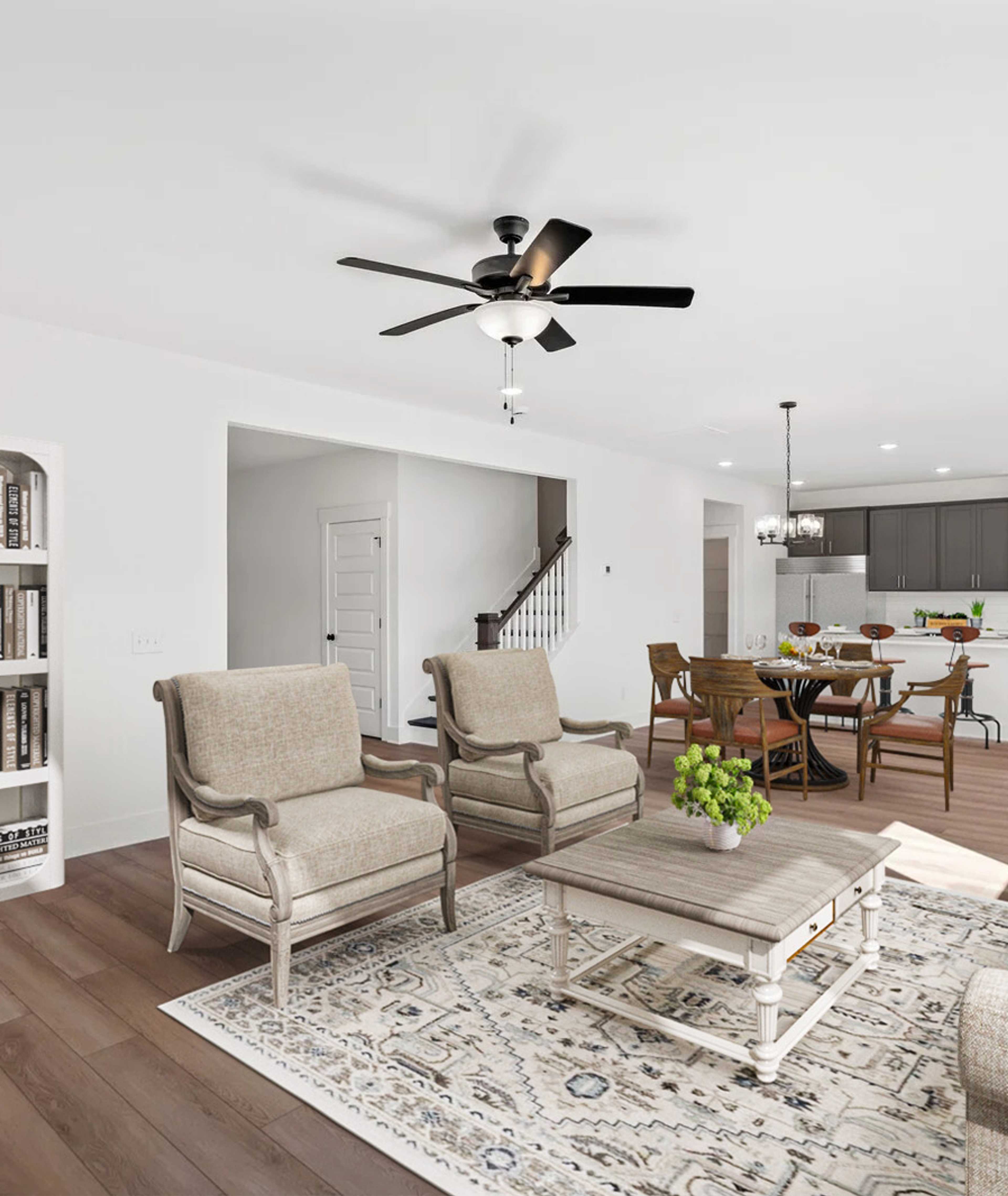 Open-concept living room in Carellton Gallatin TN home with hardwood floors, beige armchairs, white bookshelves, rug, and ceiling fan