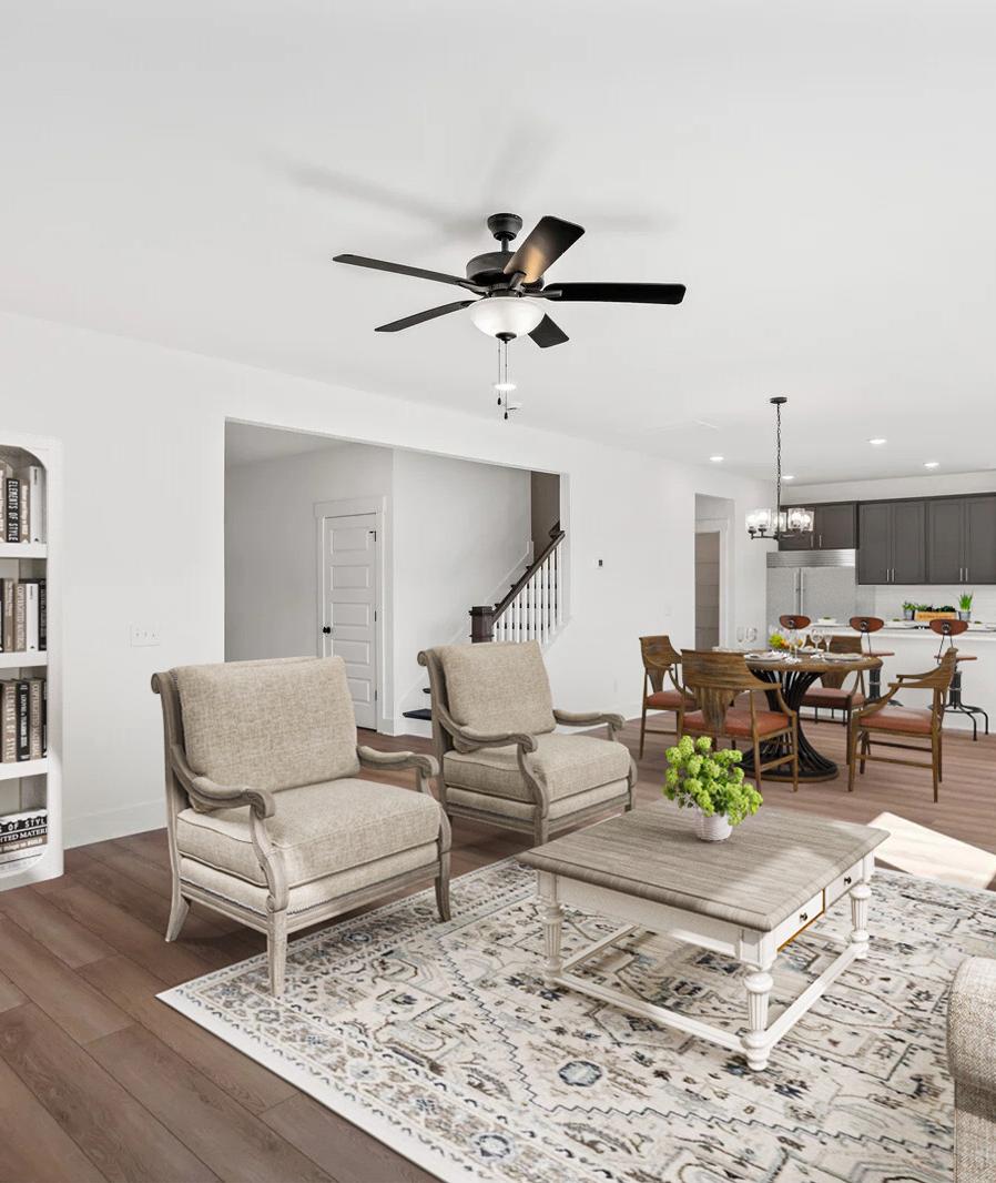 Open-concept living room in Carellton Gallatin TN home with hardwood floors, beige armchairs, white bookshelves, rug, and ceiling fan