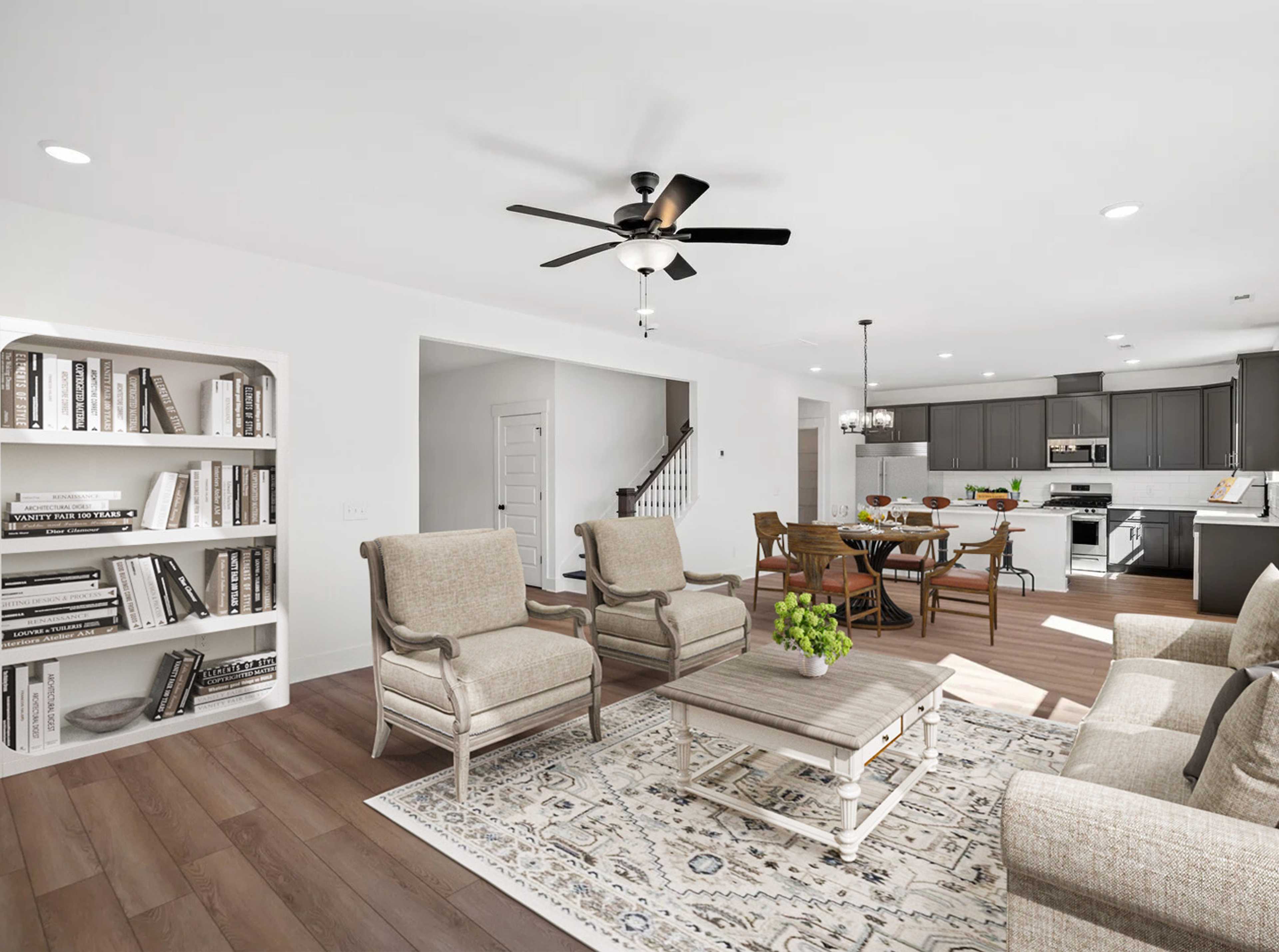 Open-concept living room in Carellton Gallatin TN home with hardwood floors, beige armchairs, white bookshelves, rug, and ceiling fan