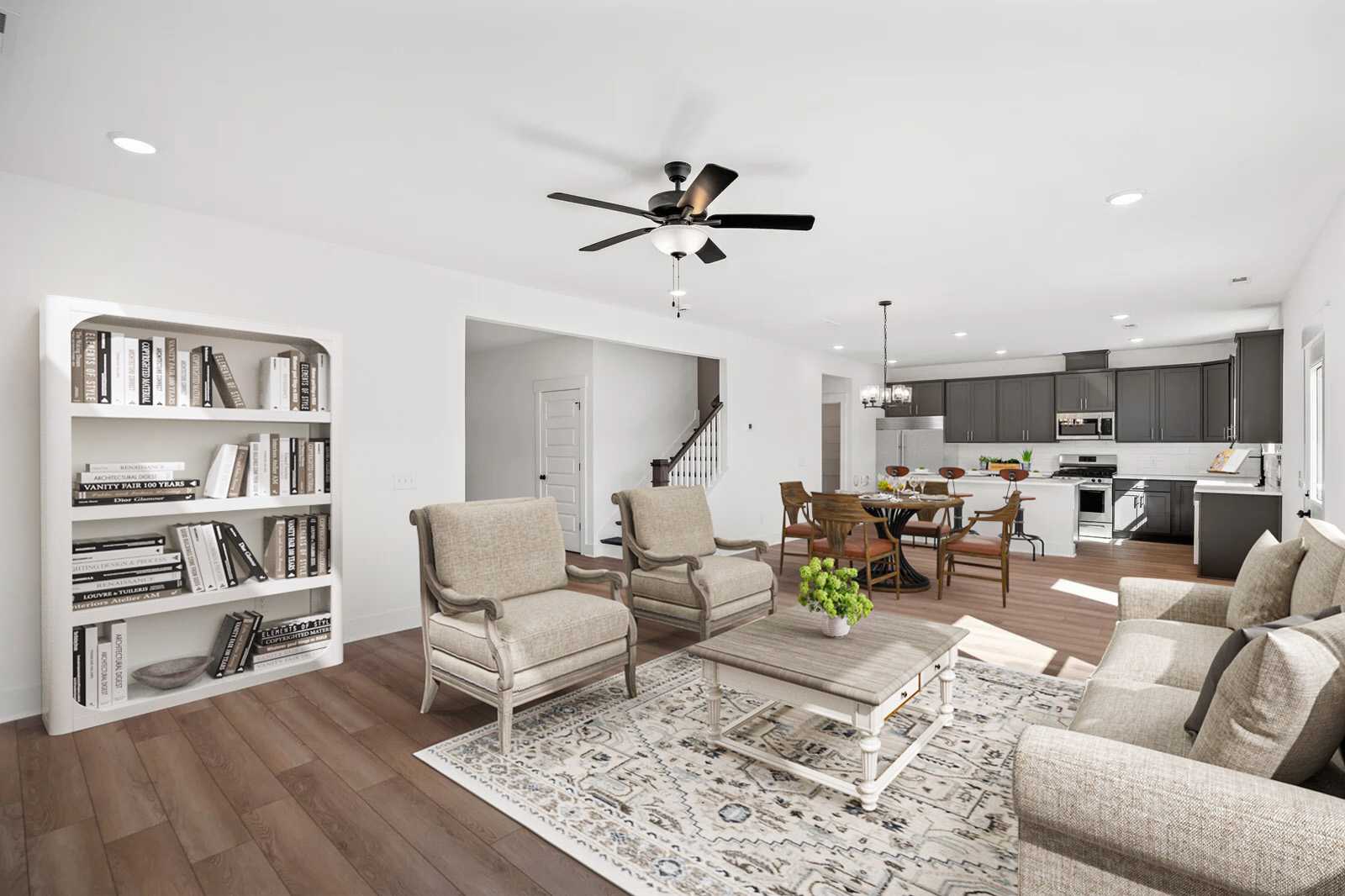 Open-concept living room in Carellton Gallatin TN home with hardwood floors, beige armchairs, white bookshelves, rug, and ceiling fan