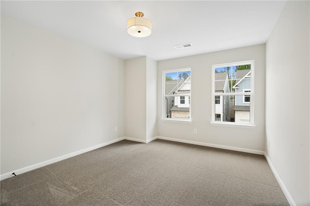 Bright secondary bedroom with large windows overlooking neighborhood in Davidson Homes The Marion A, Kennesaw, Georgia