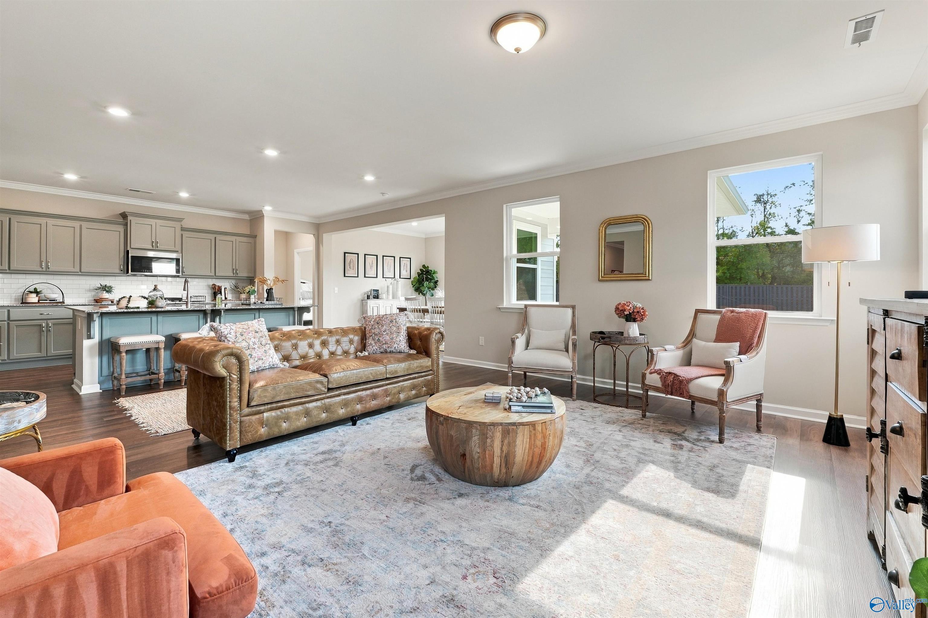 Open-concept living room with leather sofa and kitchen view in Davidson Homes The Arcadia E, Riverton Preserve, Huntsville