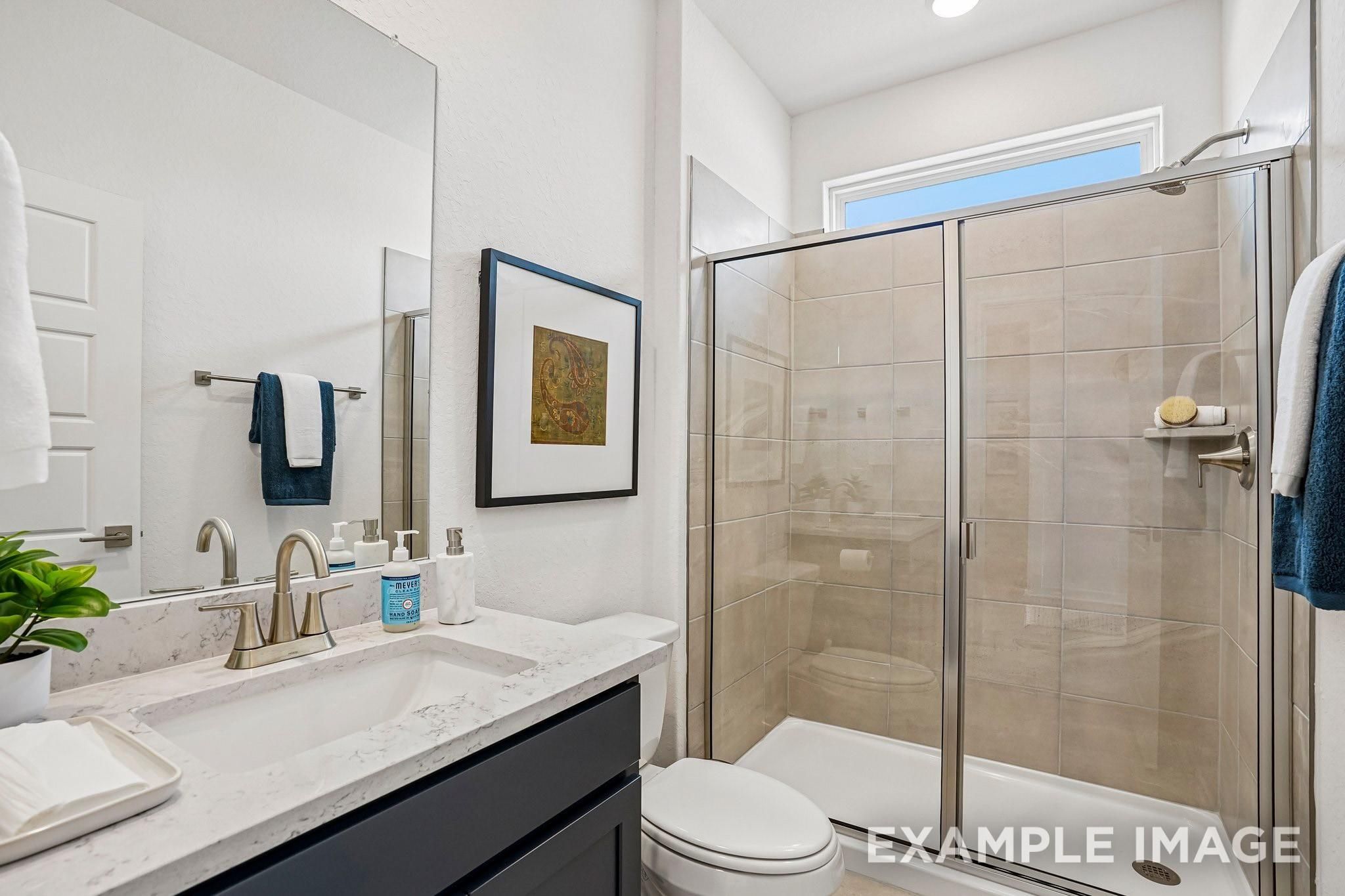 Modern bathroom with marble vanity, glass walk-in shower, and tile surround in The Ashport J home, Sundance Cove, Crosby, TX