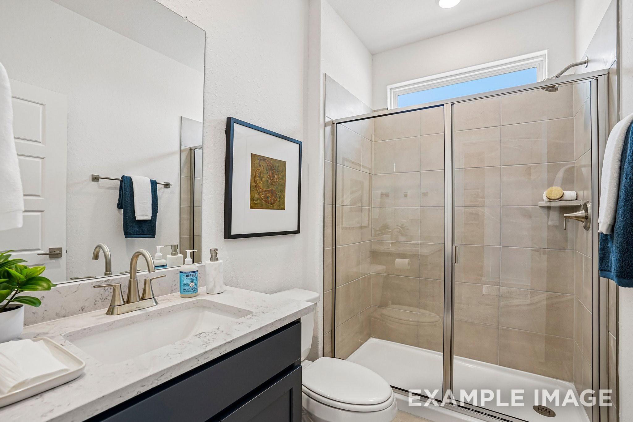Modern bathroom with marble vanity, glass walk-in shower, and tile surround in The Ashport J home, Sundance Cove, Crosby, TX