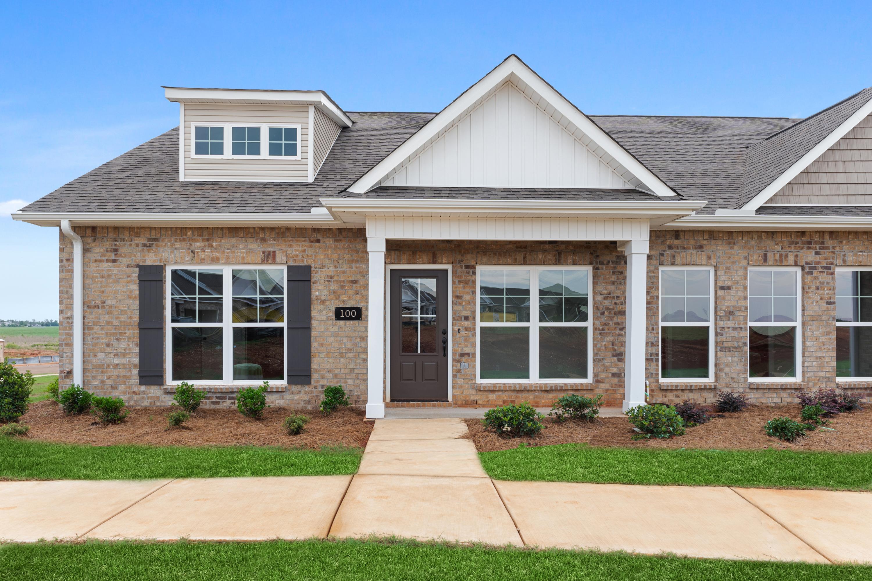Two-story Copeland multi-family home elevation with brick facade, white gable roof, dormer window, covered porch, and landscaped entry