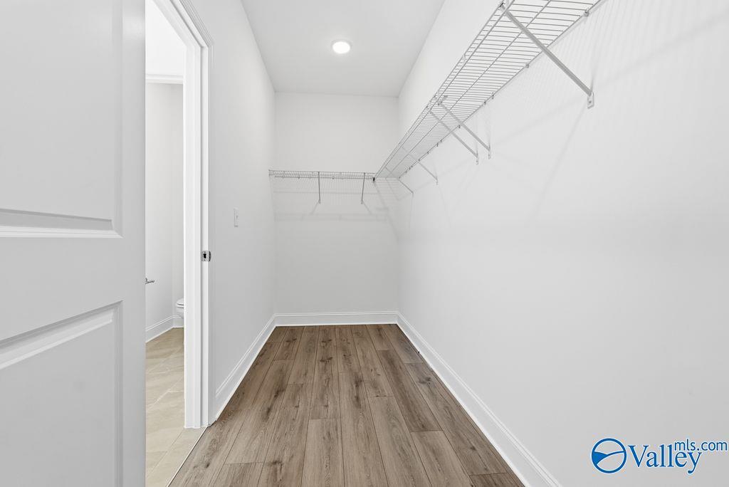 Spacious walk-in closet with wire shelving, hardwood floors, and white walls in Davidson Homes The Montgomery, Hartselle, AL