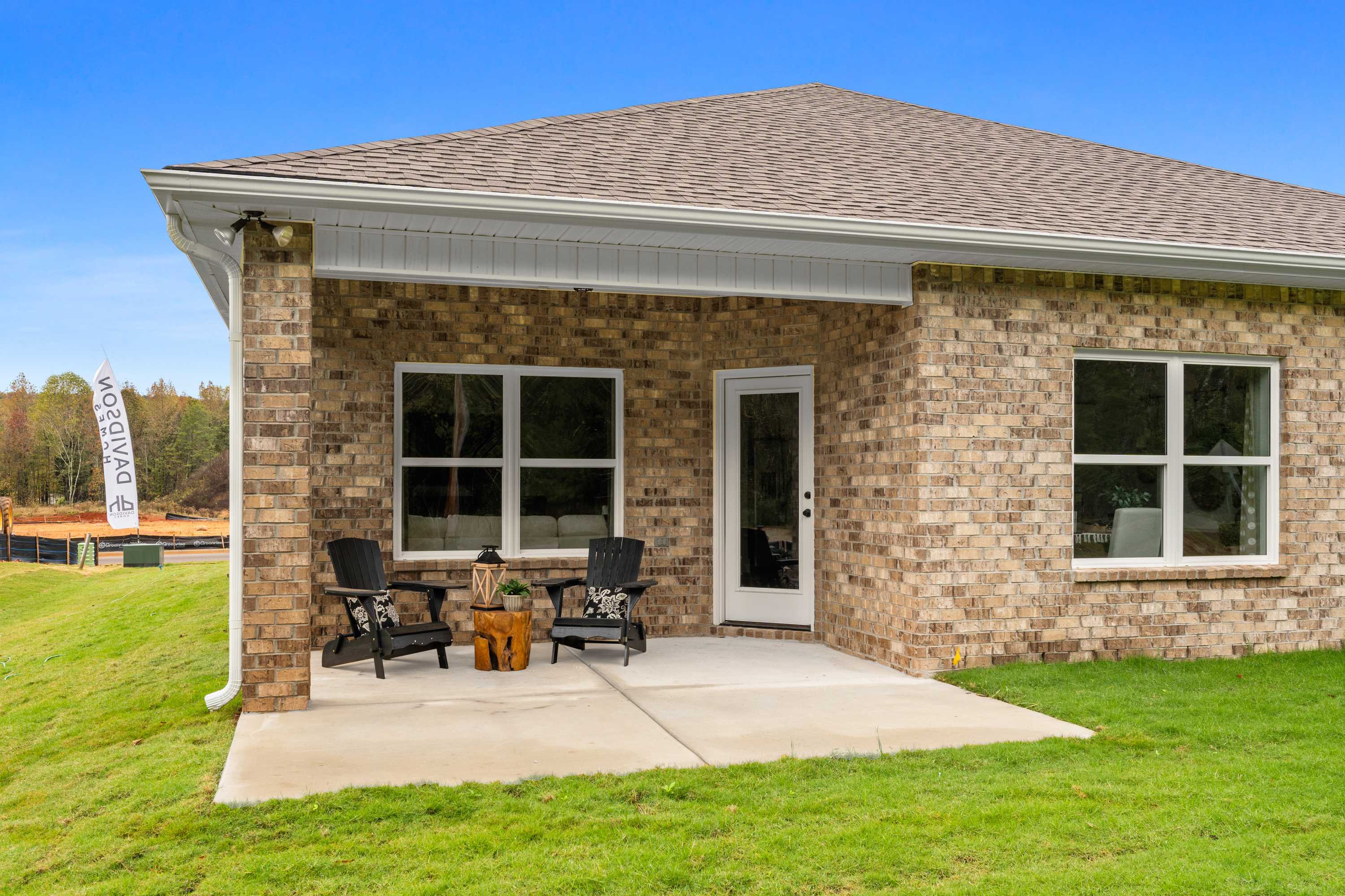 Modern brick home exterior at Spragins Cove in Huntsville, Alabama with covered porch, Adirondack chairs and green lawn