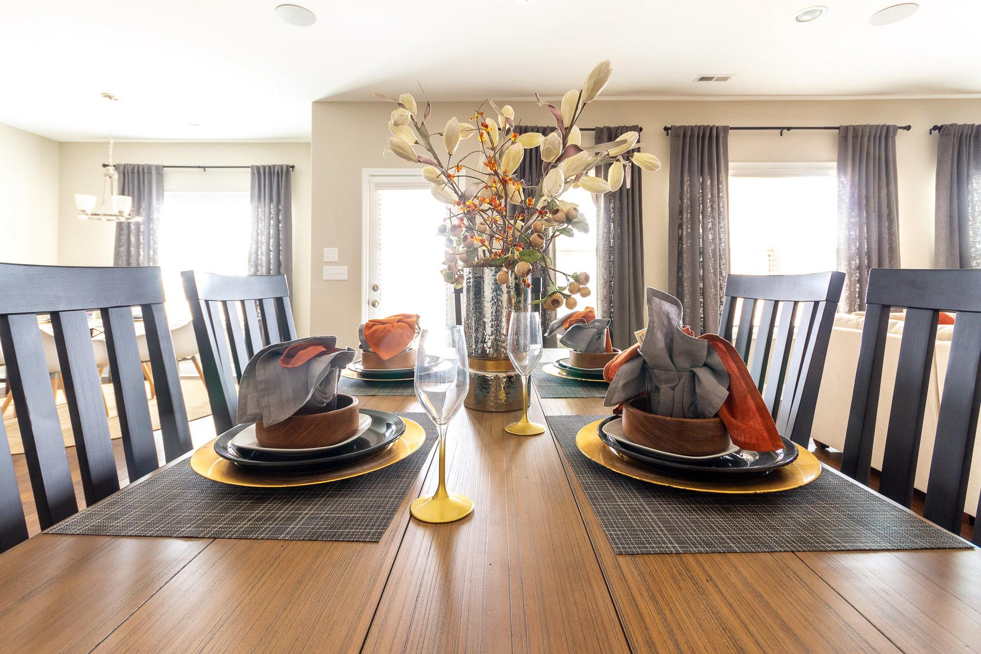 Elegant dining room at Summer Pointe in Madison Alabama with wooden table set for dinner, orange napkins and fall floral centerpiece