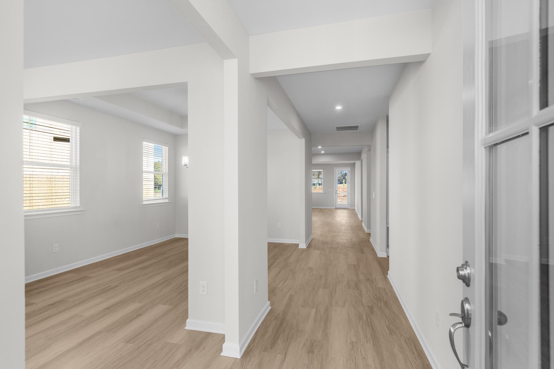 Spacious entry hallway in The Glenwood A with light oak floors, white walls, arched openings, and adjacent rooms
