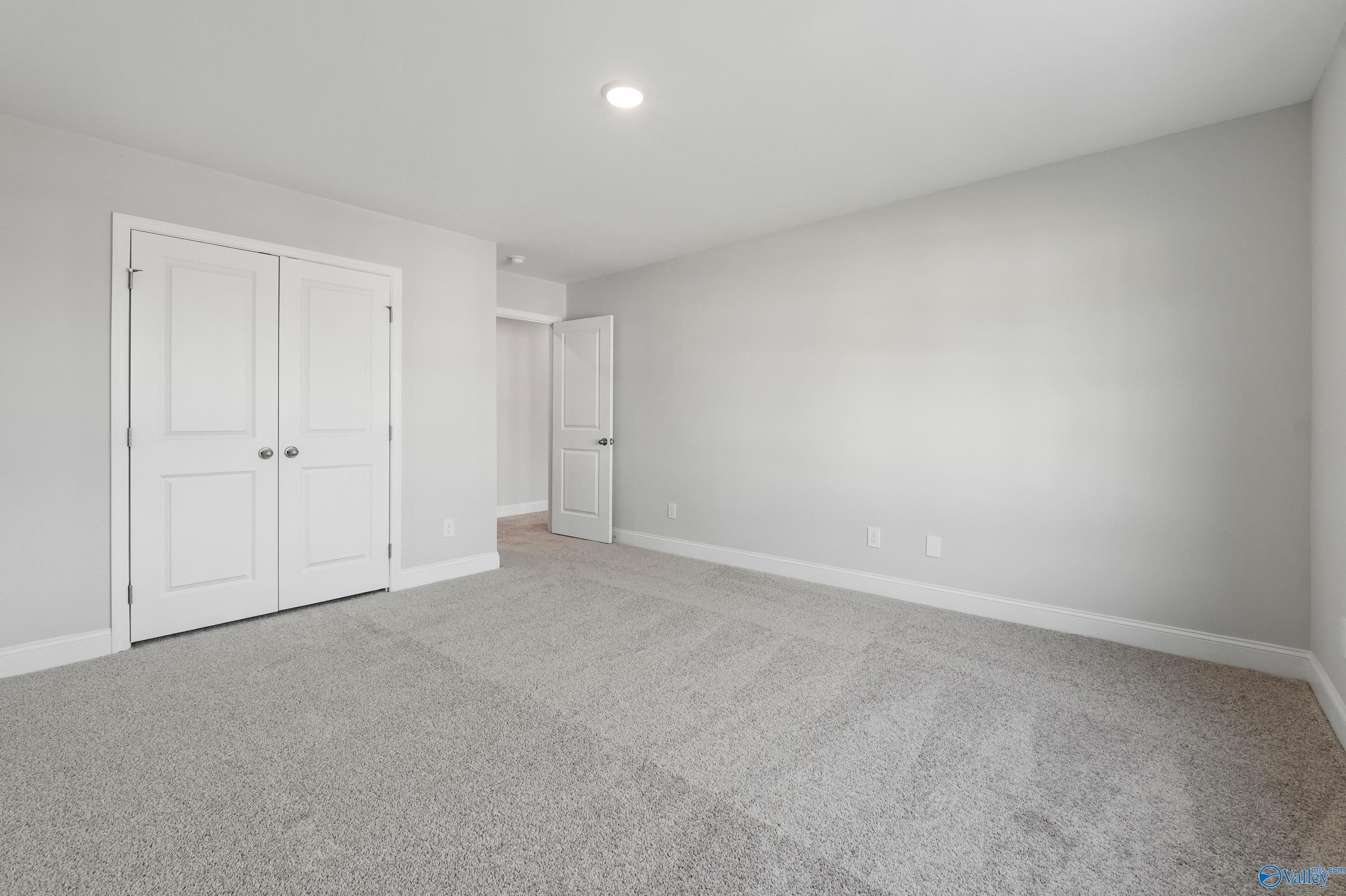 Spacious bedroom with double-door closet, neutral gray walls, and plush carpet in Davidson Homes The Camden B, Huntsville AL