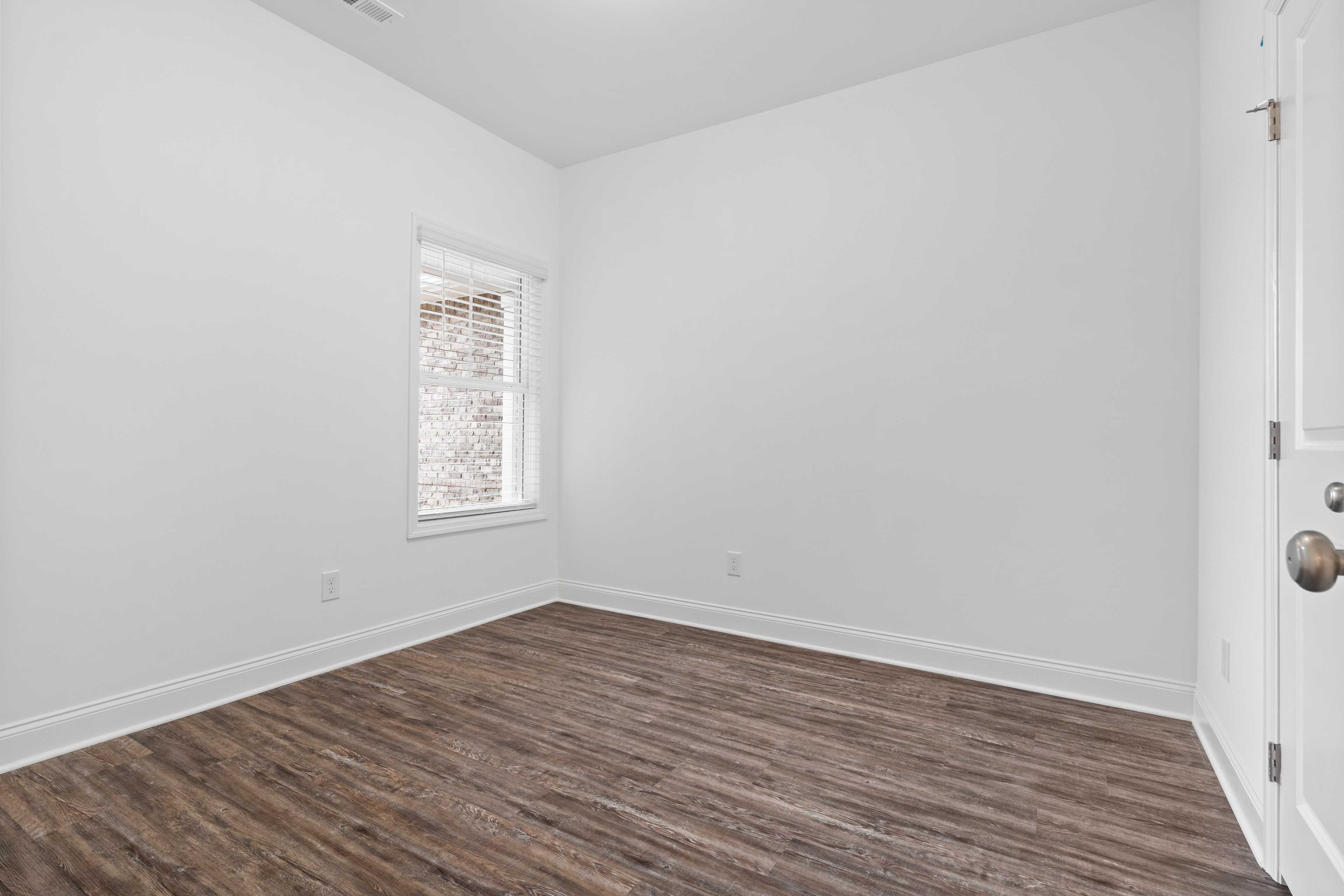 Spacious empty bedroom at The Retreat at Hollon Meadow in Decatur Alabama with white walls luxury vinyl plank flooring and window blinds