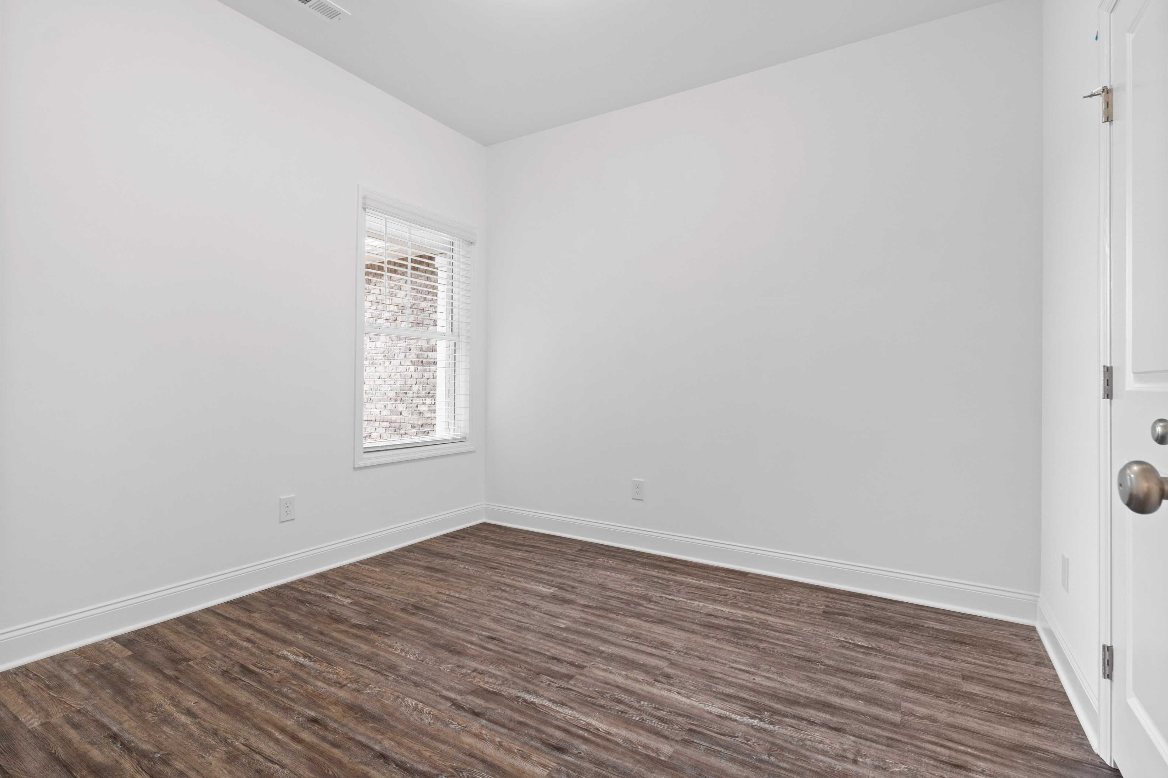 Spacious empty bedroom at The Retreat at Hollon Meadow in Decatur Alabama with white walls luxury vinyl plank flooring and window blinds