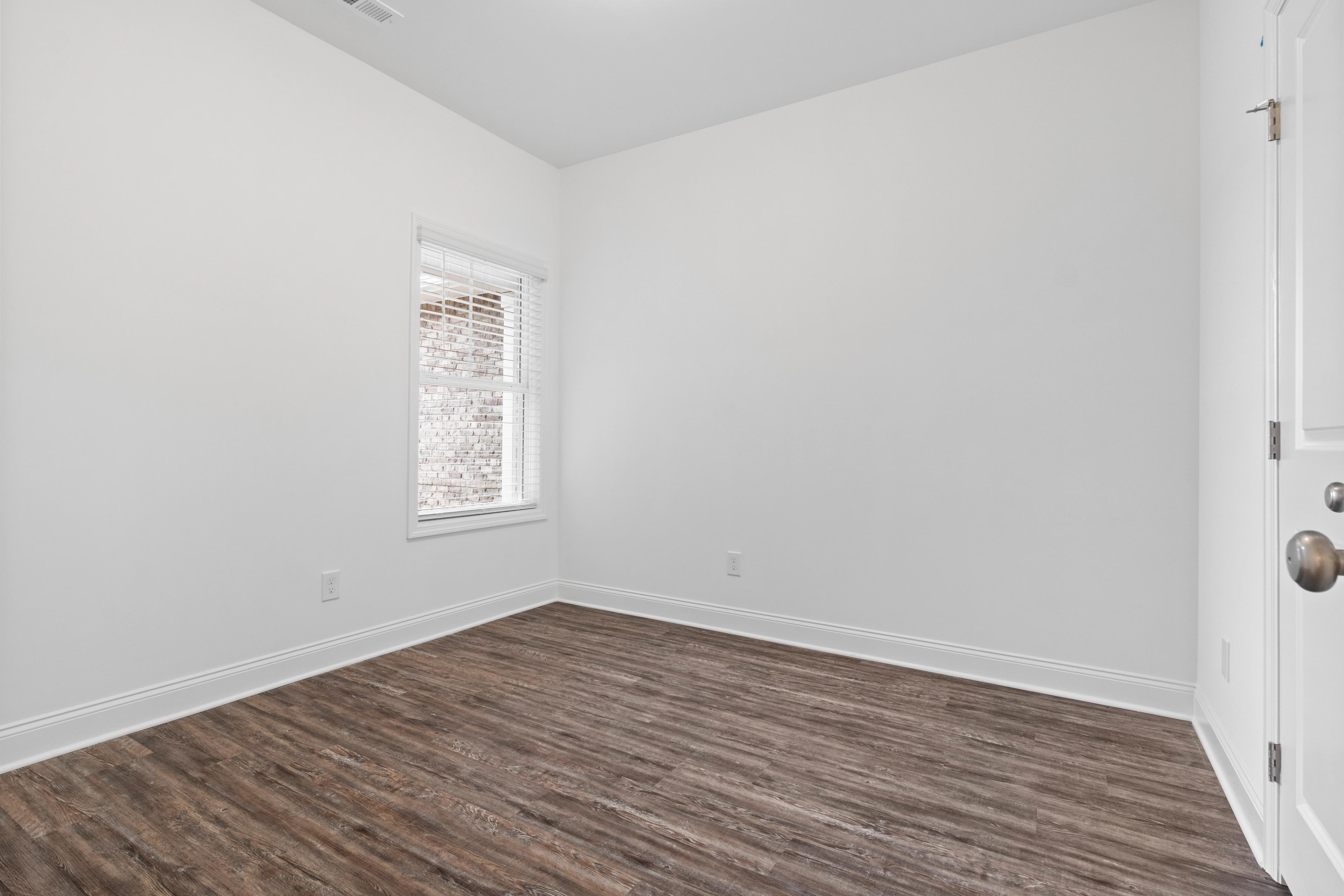 Spacious empty bedroom at The Retreat at Hollon Meadow in Decatur Alabama with white walls luxury vinyl plank flooring and window blinds
