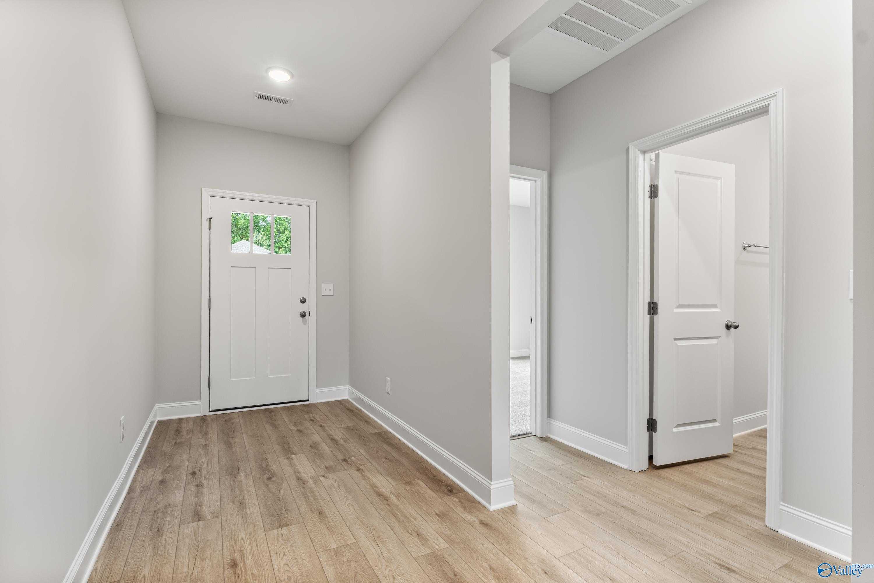 Bright entry hallway with hardwood floors, neutral walls, and open doorways in Davidson Homes The Daphne C, Athens, Alabama