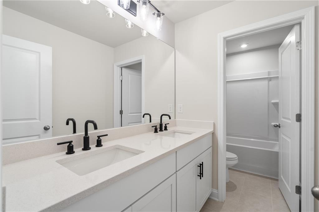 Modern double vanity with quartz countertop, black faucets, and large mirror in The Hickory E bathroom, Davidson Homes, Buford, GA