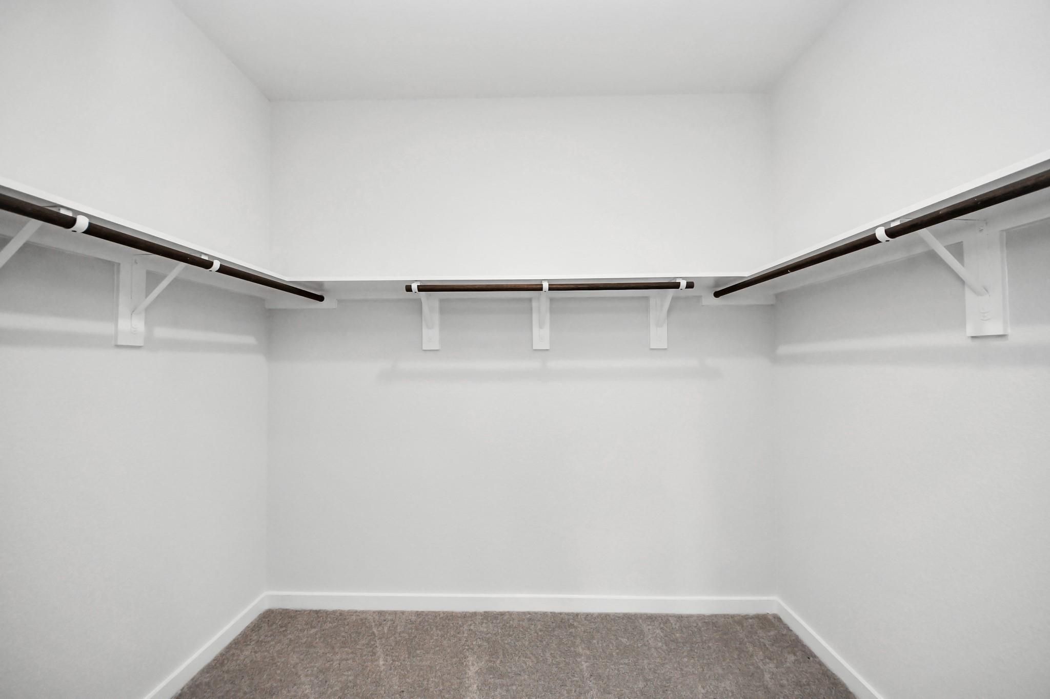 Spacious walk-in closet with built-in shelving in The Brazos F floor plan at Liberty Estates, Cleveland, Texas.