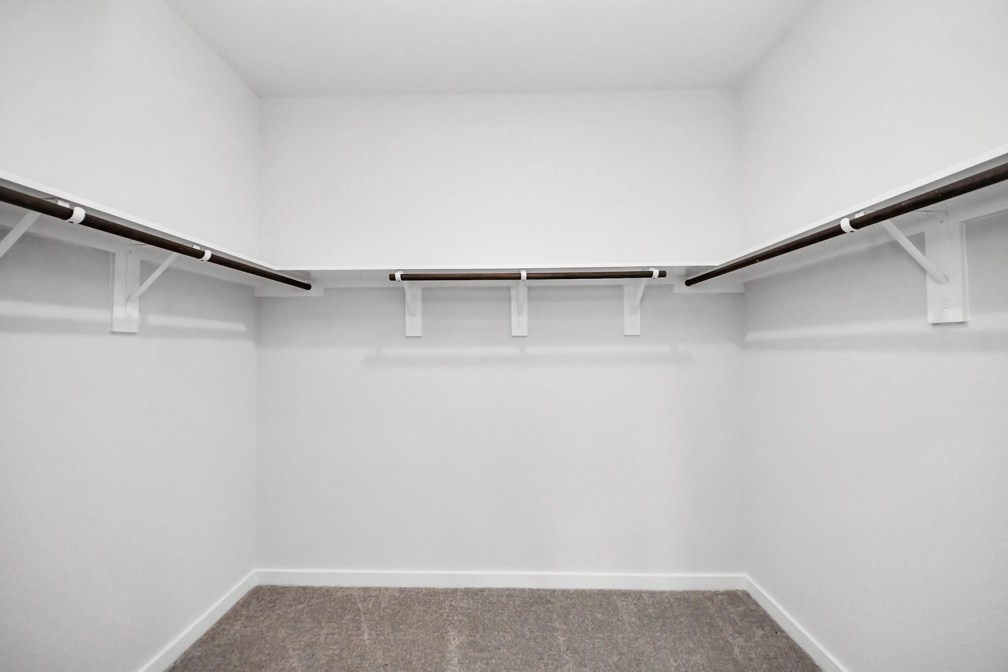 Spacious walk-in closet with built-in shelving in The Brazos F floor plan at Liberty Estates, Cleveland, Texas.