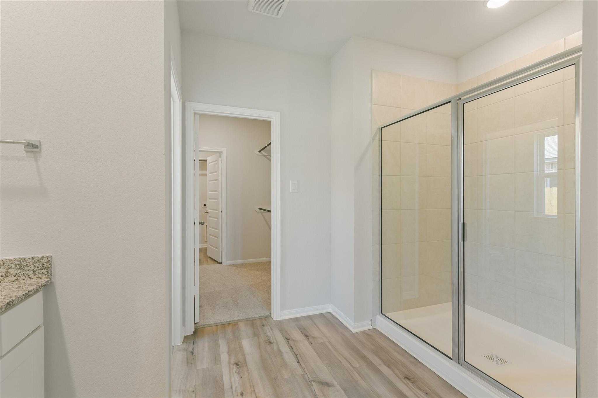 Modern master bathroom with frameless glass walk-in shower and granite vanity in Davidson Homes The Laguna B, Dayton Texas