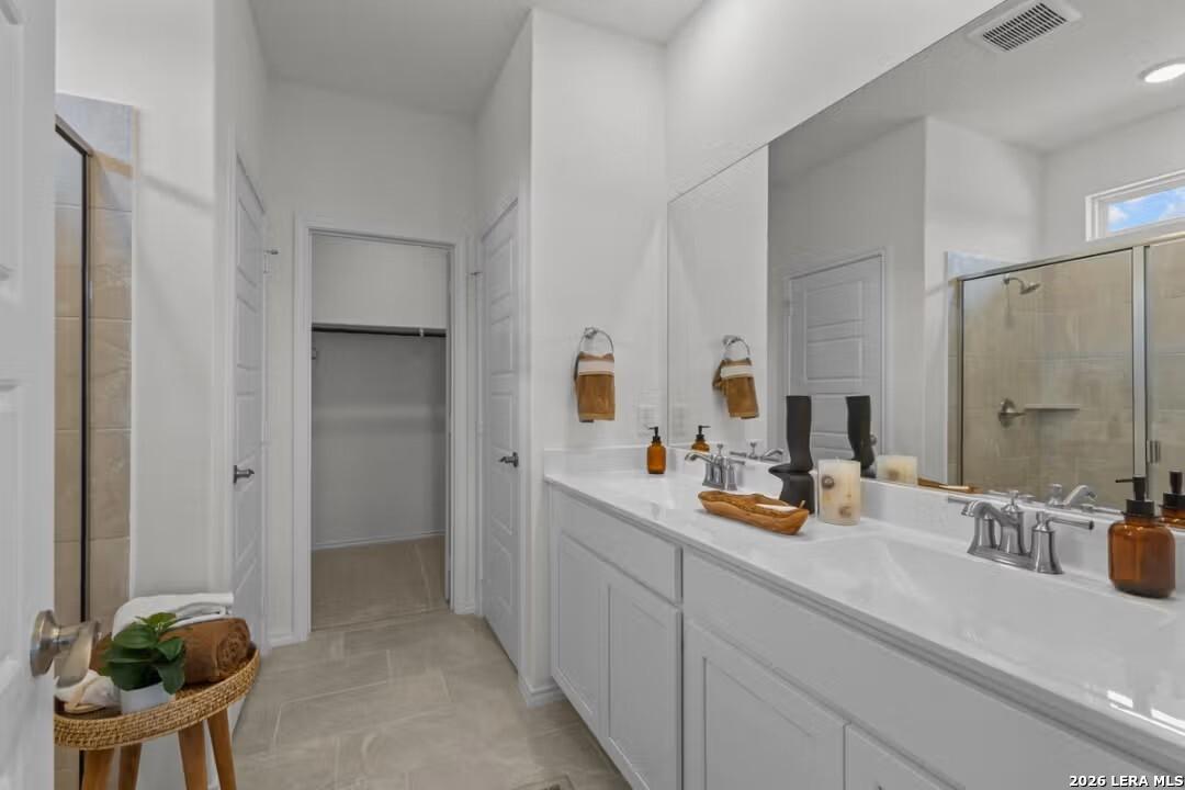 Spacious primary bathroom with dual vanity, frameless shower, and walk-in closet in Davidson Homes The Daphne H, Seguin, Texas