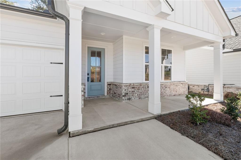 Modern farmhouse home front with blue door, brick accents, covered porch, columns, and 2-car garage in Kelly Preserve, Loganville, Georgia