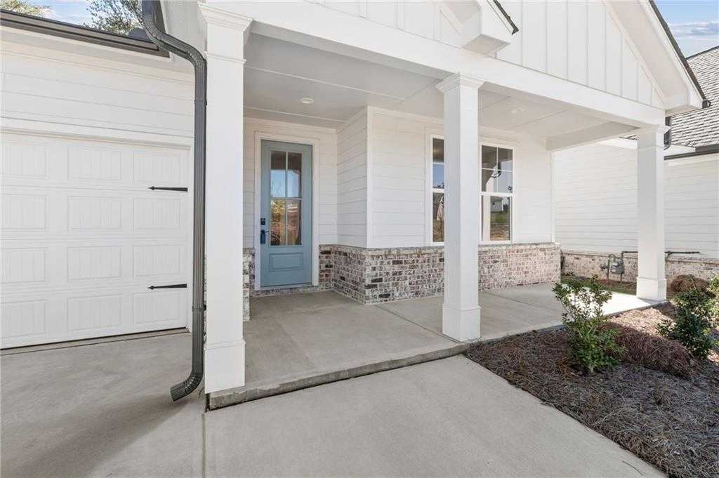 Modern farmhouse home front with blue door, brick accents, covered porch, columns, and 2-car garage in Kelly Preserve, Loganville, Georgia