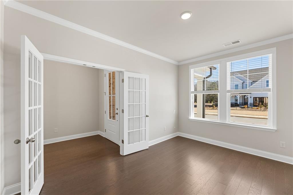Elegant flex room with open French doors, hardwood floors, and large windows overlooking neighborhood in Davidson Homes The Harrison G, Hoschton, GA