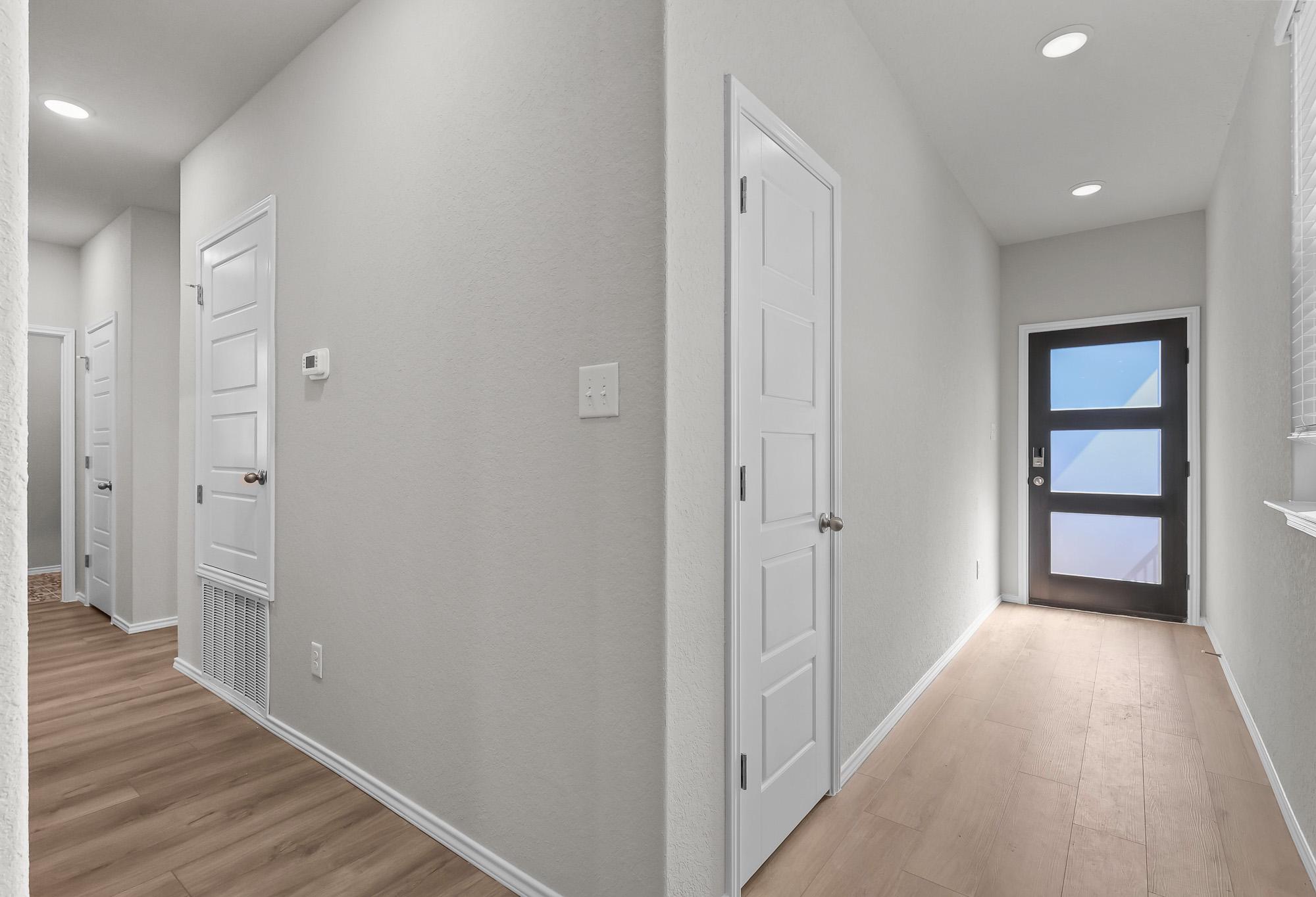 Bright entryway and hallway in The Colorado B by Davidson Homes featuring modern front door, light flooring, and clean walls.