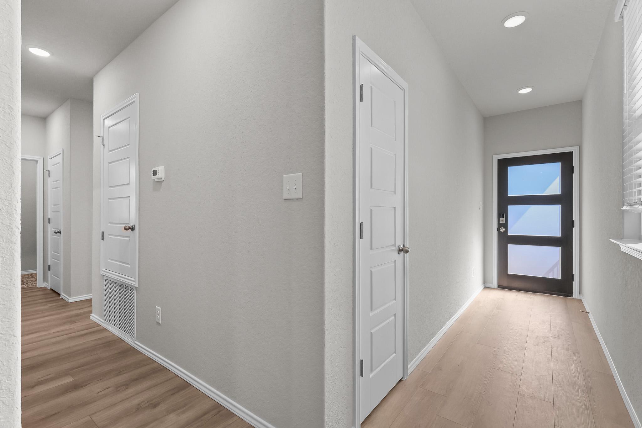 Bright entryway and hallway in The Colorado B by Davidson Homes featuring modern front door, light flooring, and clean walls.