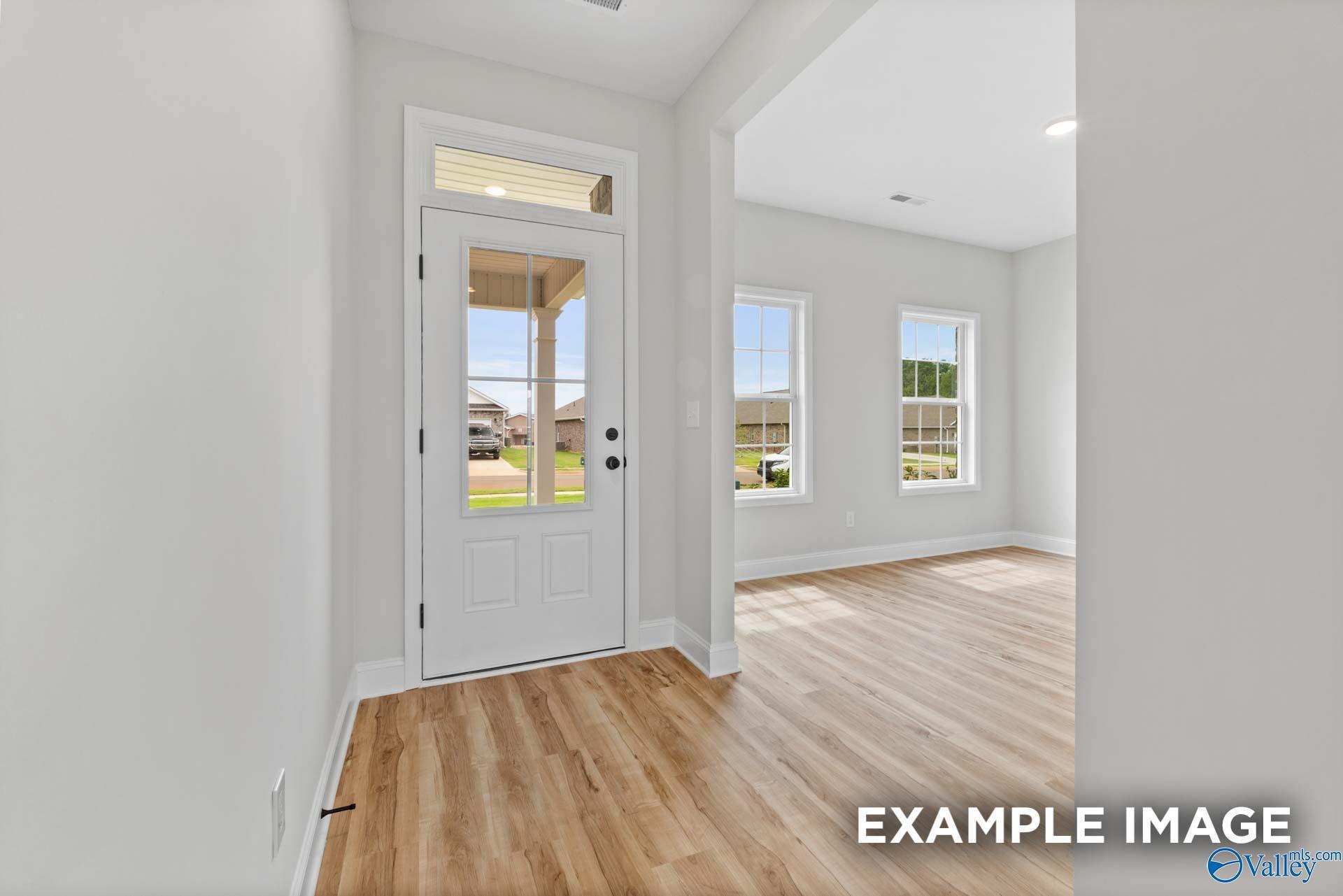 Bright entryway with white front door and wood-look flooring in The Shelby B floor plan at Jaguar Hills, Huntsville.