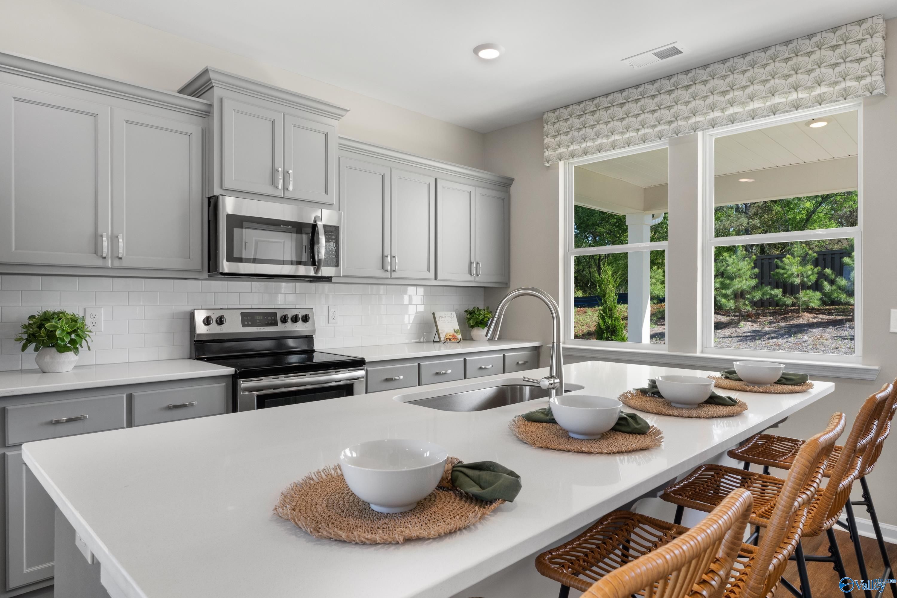 Modern gray kitchen with white quartz island, stainless steel appliances, subway tile backsplash in The Stella, Madison AL
