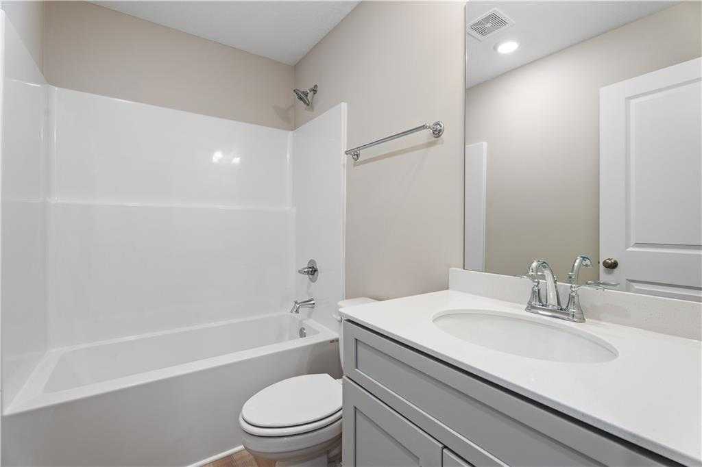Bright bathroom with white tub-shower combo, gray vanity, and toilet in Davidson Homes The Bartlett, Phenix City, Alabama