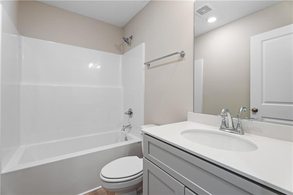 Bright bathroom with white tub-shower combo, gray vanity, and toilet in Davidson Homes The Bartlett, Phenix City, Alabama