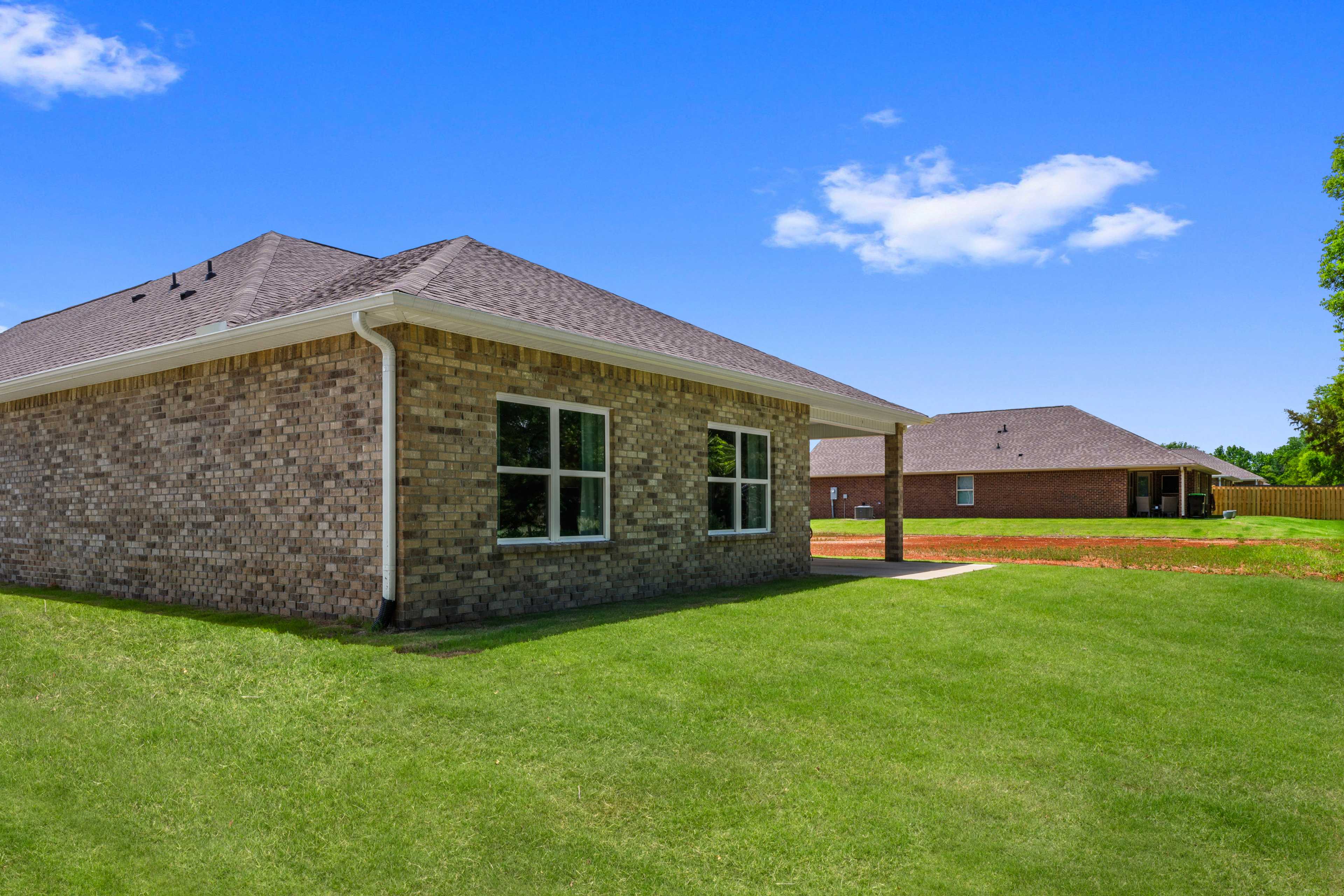 Brick home exterior at Hollon Meadow in Decatur Alabama with gabled roof, large windows, green lawn, and neighboring house