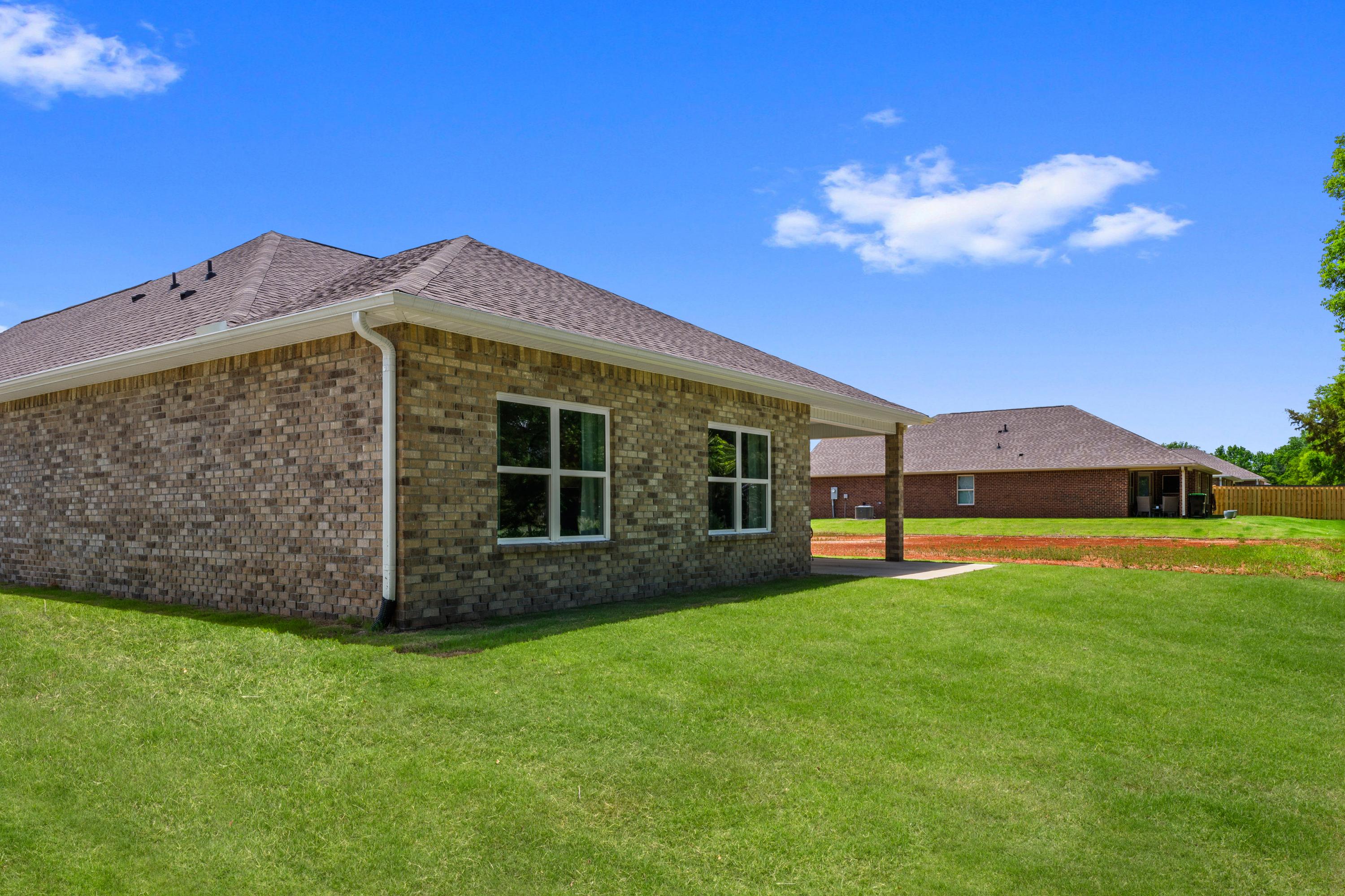 Brick home exterior at Hollon Meadow in Decatur Alabama with gabled roof, large windows, green lawn, and neighboring house
