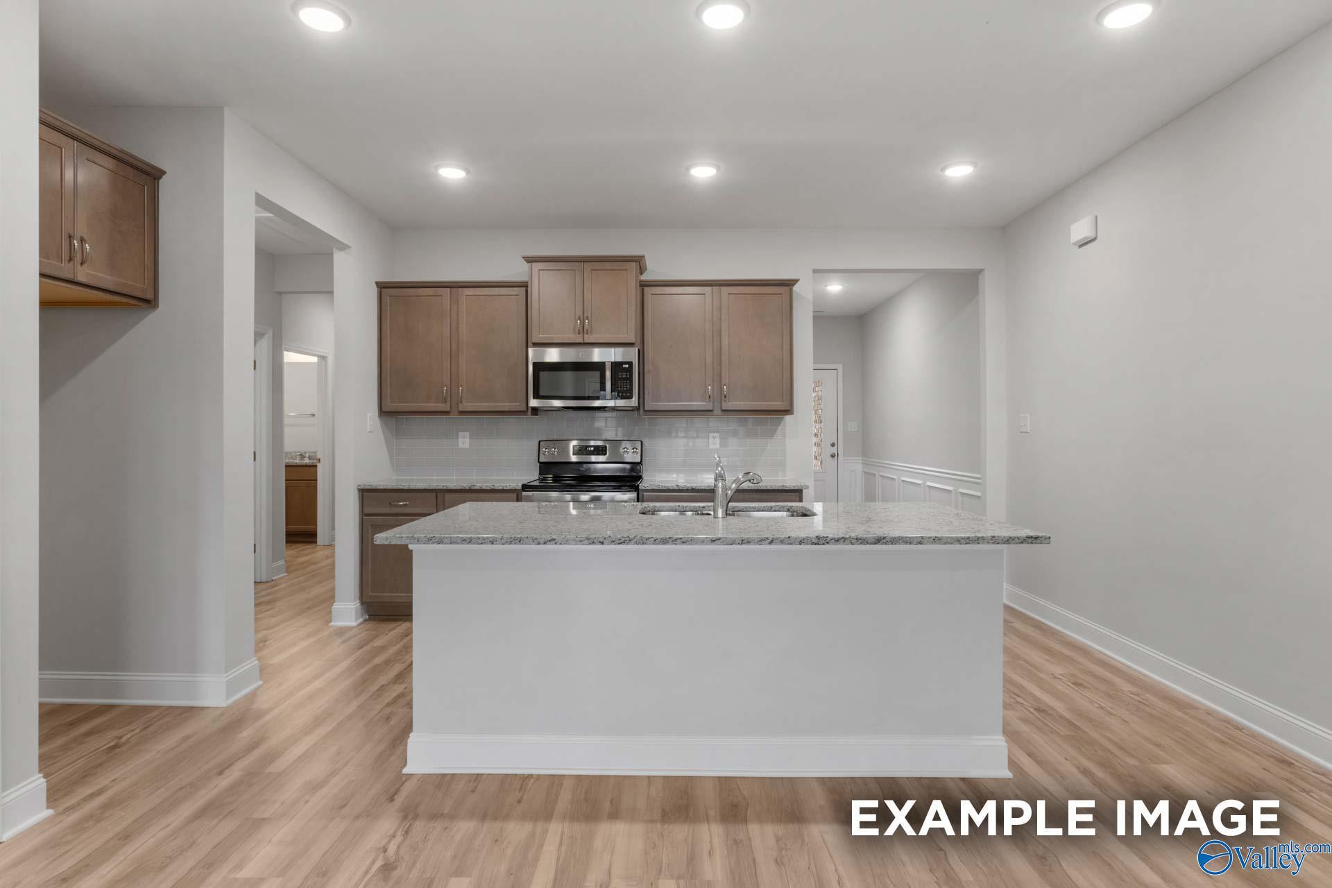Modern open-concept kitchen with white shaker cabinets, granite island, stainless appliances in The Cumberland B by Davidson Homes, Decatur, AL