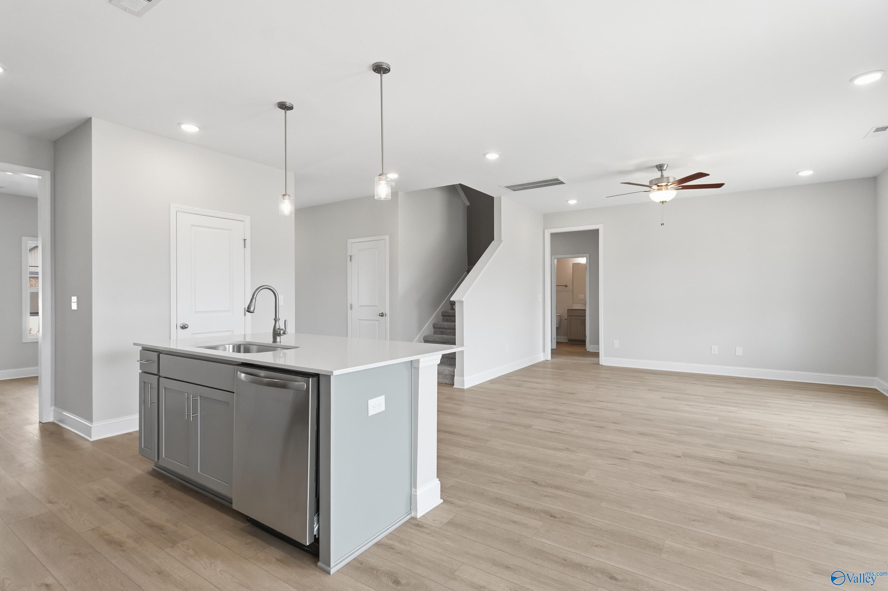 Modern open kitchen with gray island, stainless sink, dishwasher in The Shelby B 4-bedroom home, Creek Grove, New Market, Alabama