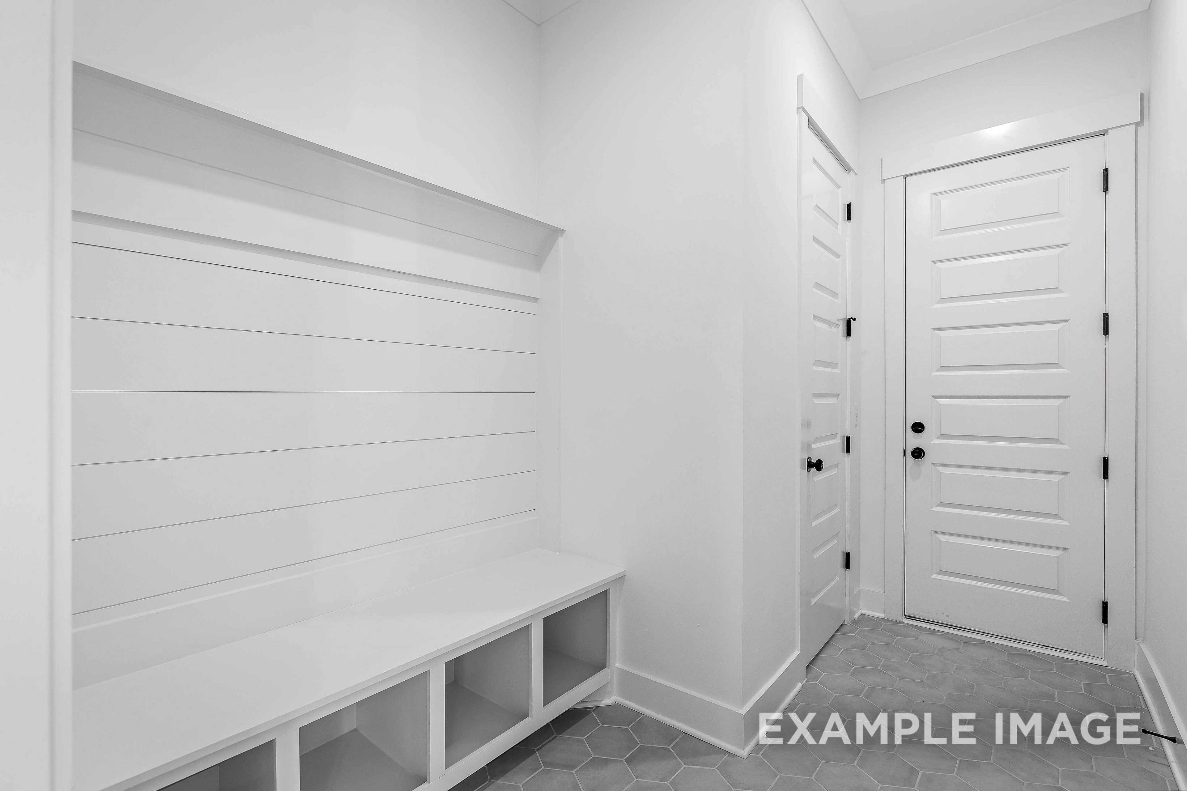 Modern mudroom in The Albany A home design featuring white built-in bench, cubbies, shiplap walls, and entry door