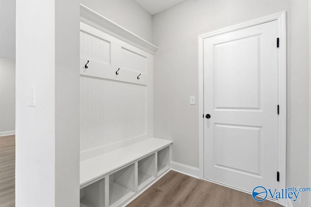 White mudroom with built-in bench, coat hooks, and storage shelves in Davidson Homes The Montgomery B, Hartselle, Alabama
