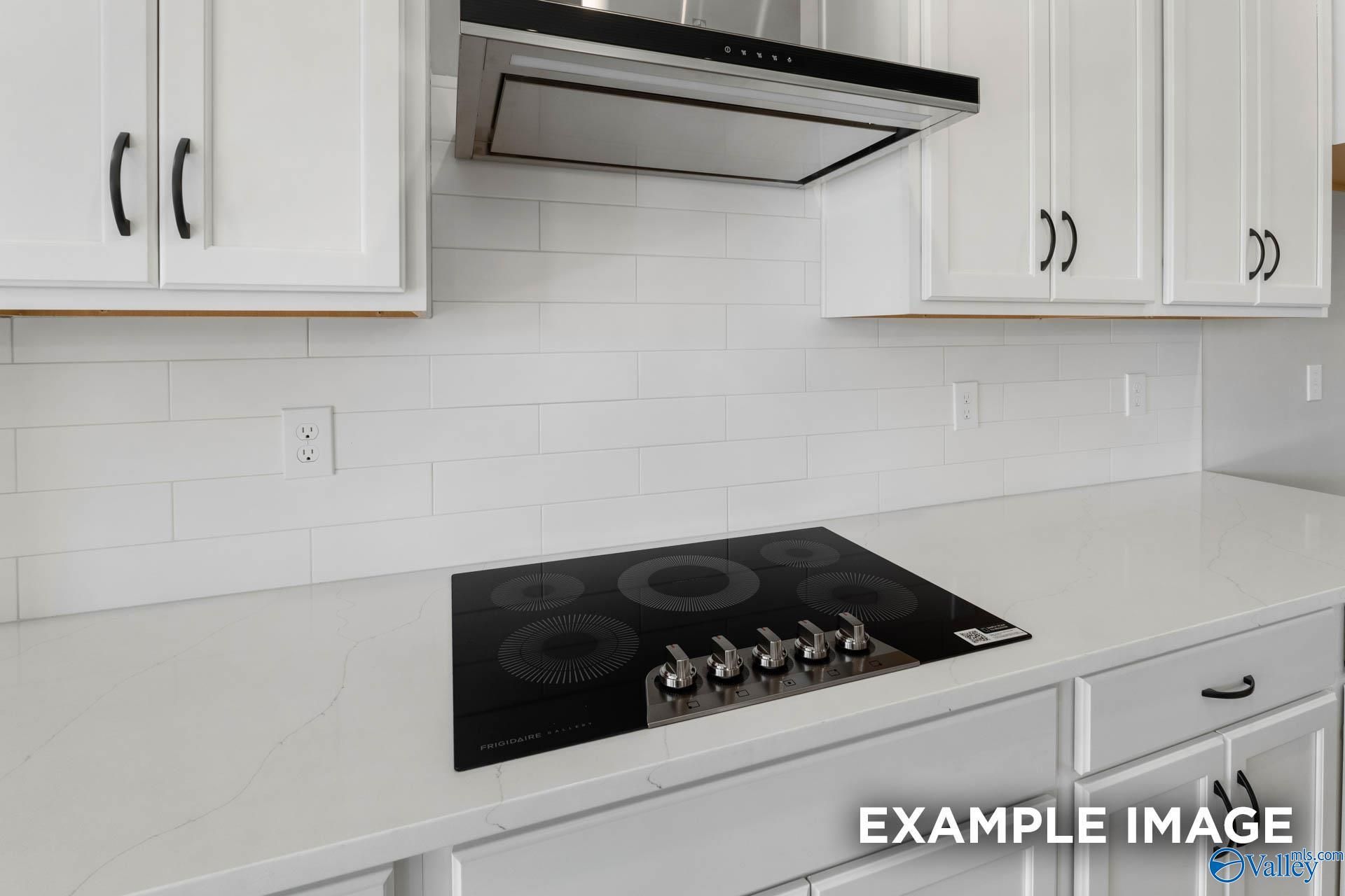 Modern kitchen with white cabinets, quartz countertops, and electric cooktop in The Finleigh floor plan, Meridianville, AL.