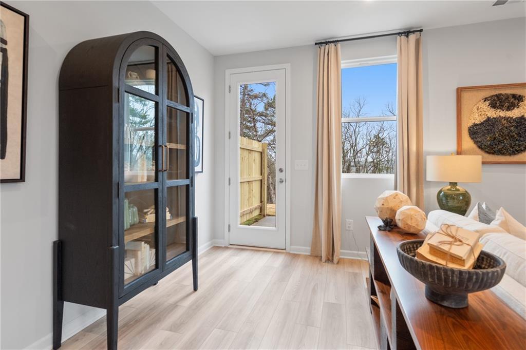 Elegant entryway with arched gray armoire, wooden console table, decor accents, and French doors to fenced yard in Davidson Homes Wilmington B, Emerson, GA