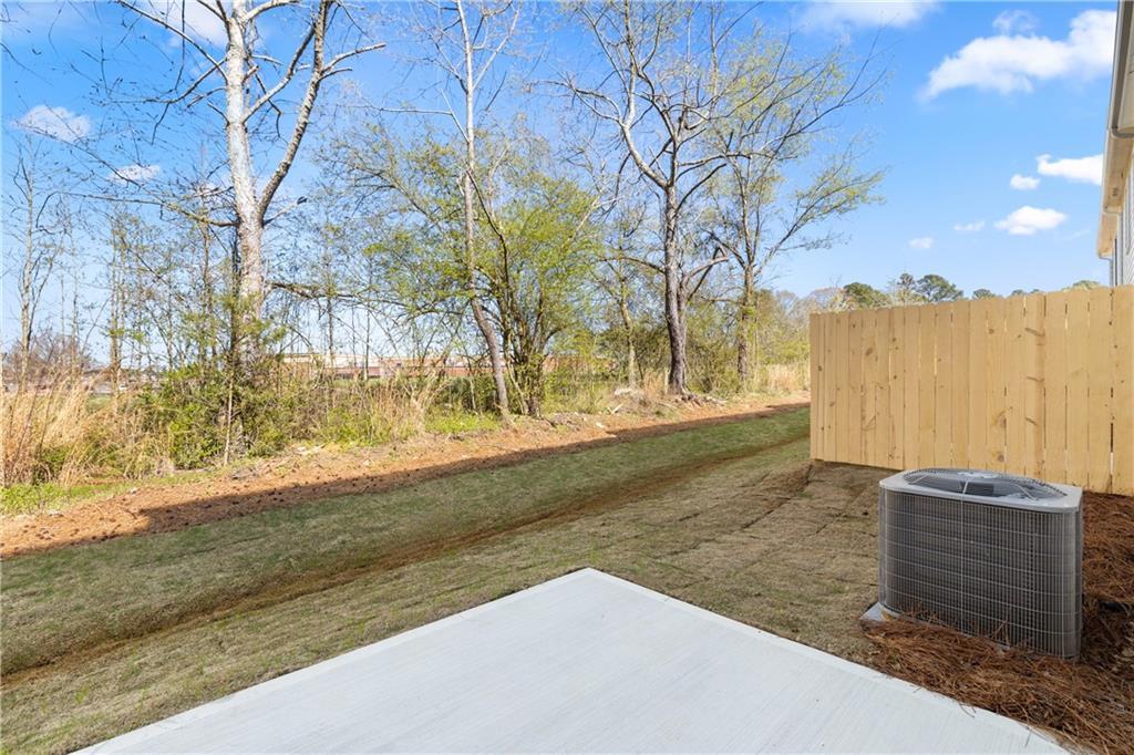 Private backyard with wooden privacy fence, mature trees, and AC unit beside Cary A home in Lake Shore, Winder, Georgia