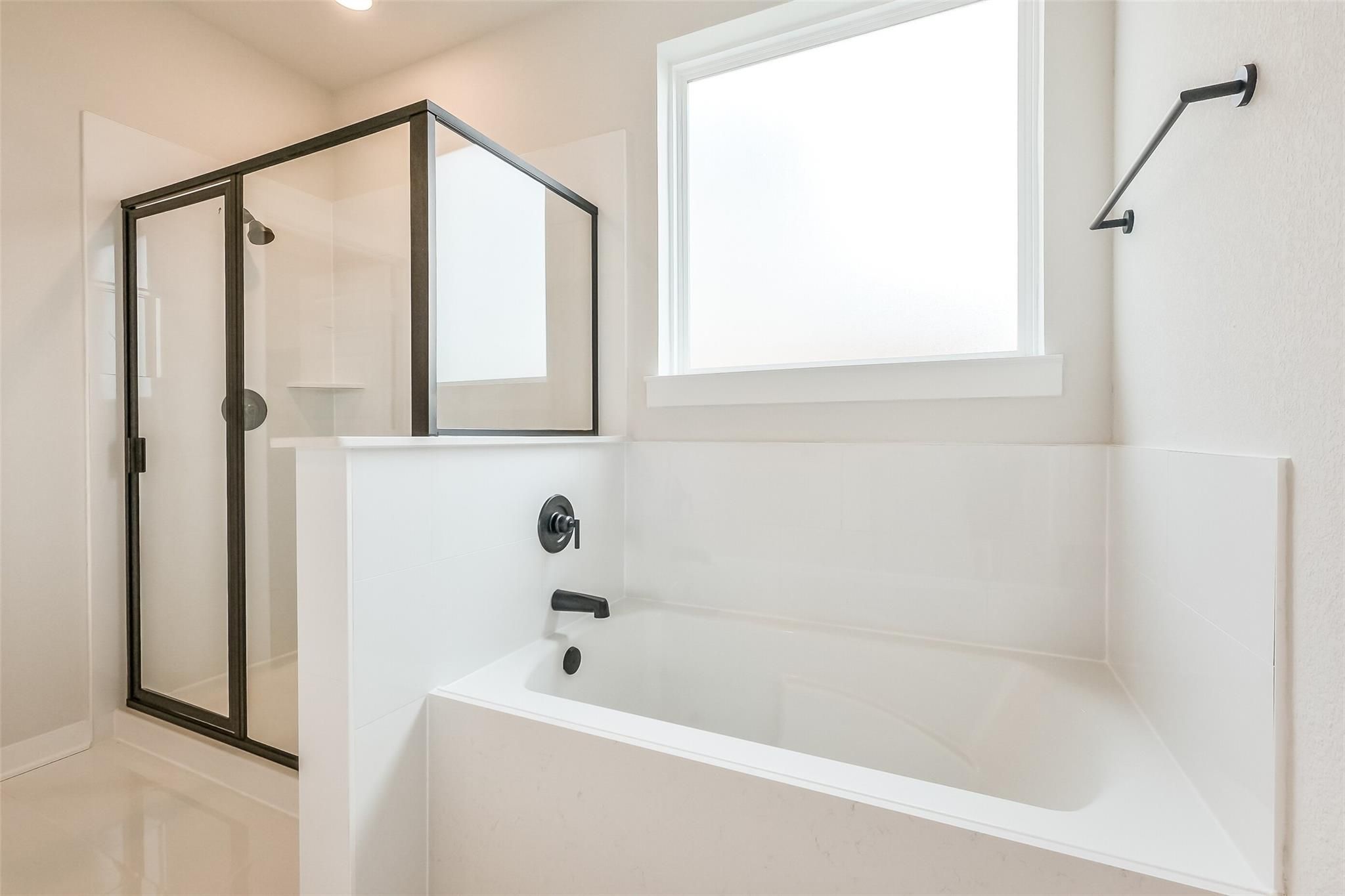 Modern master bathroom featuring frameless glass shower, deep soaking tub, and white subway tiles in Davidson Homes The Tierra B, Beasley, Texas
