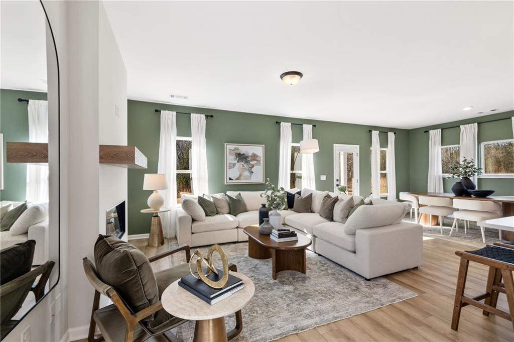 Open-concept living room with sage green walls and cozy sectional in The Rabun B floor plan at The Bluffs, Canton, Georgia.