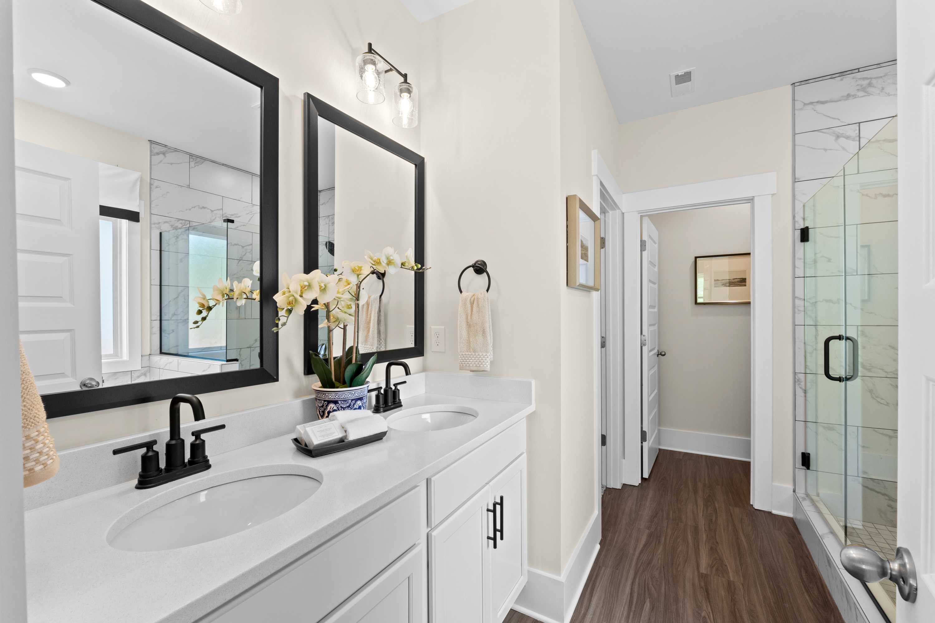 Luxury master bathroom at Ivy Hills in Toney Alabama with double vanity, marble counters, orchids, and glass shower