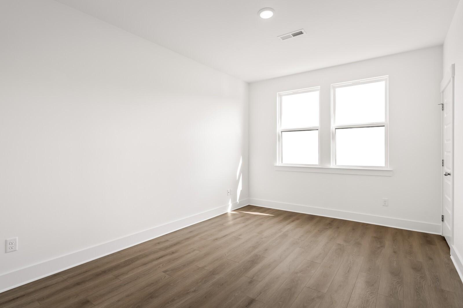 Bright empty bedroom with large double windows, white walls, and hardwood floors in The Willow D, Mt. Juliet, TN
