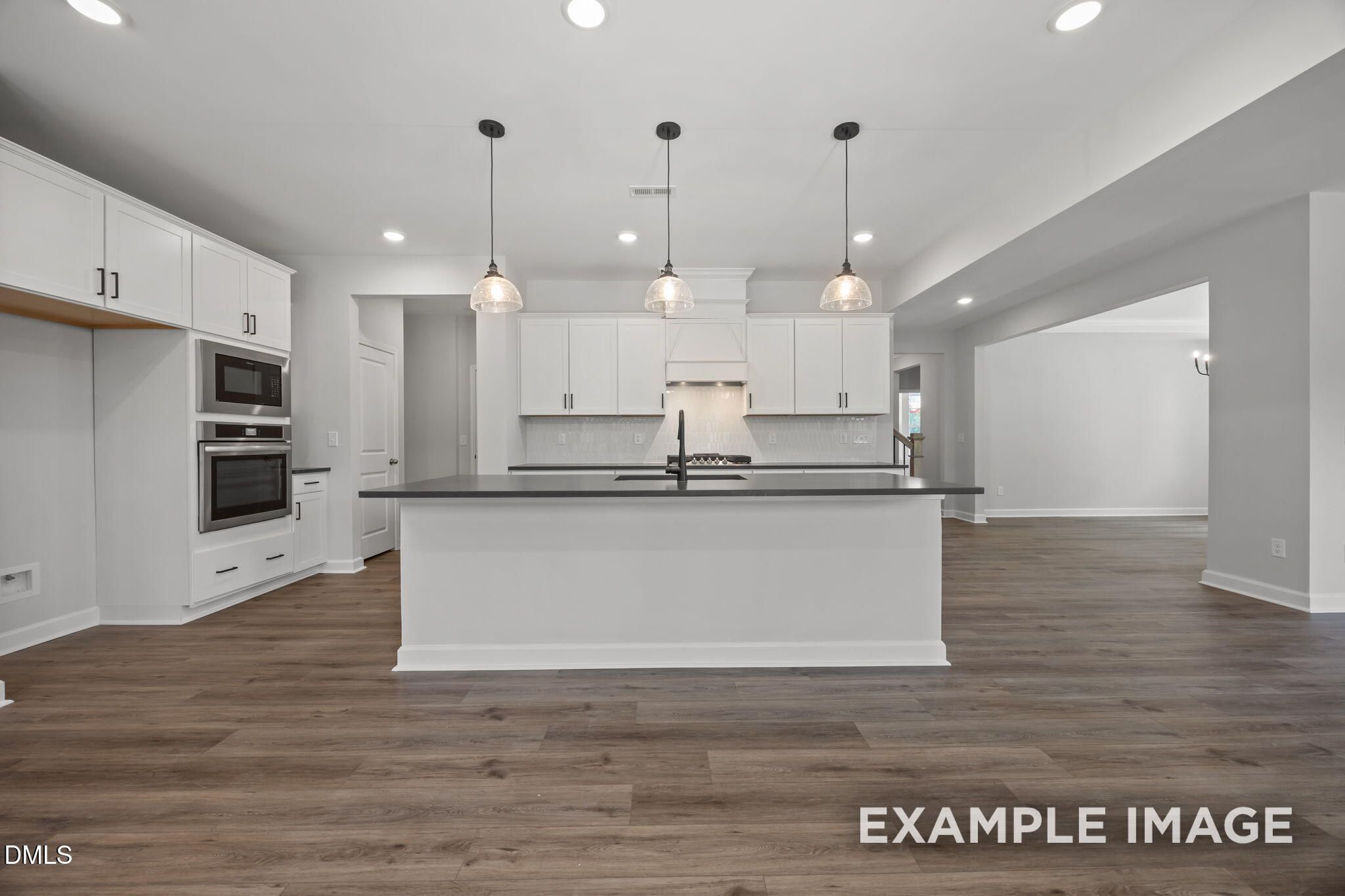 White kitchen with island, pendant lights, and luxury vinyl plank flooring in Davidson Homes The Beech plan, Wendell Ridge, NC